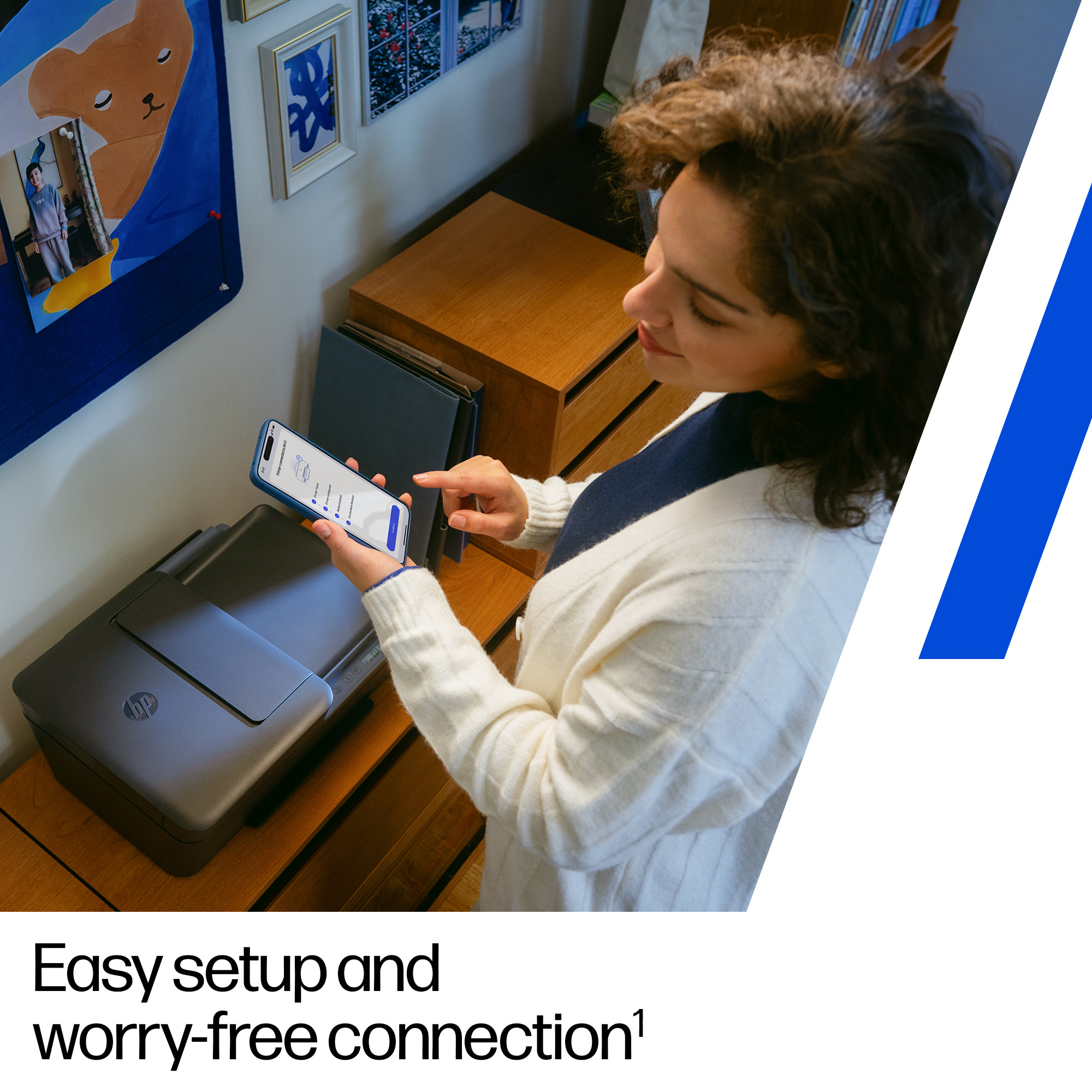 Een vrouw gebruikt een smartphone om verbinding te maken met een zwarte HP-printer. De scène bevat houten meubels en kunst aan de muur.