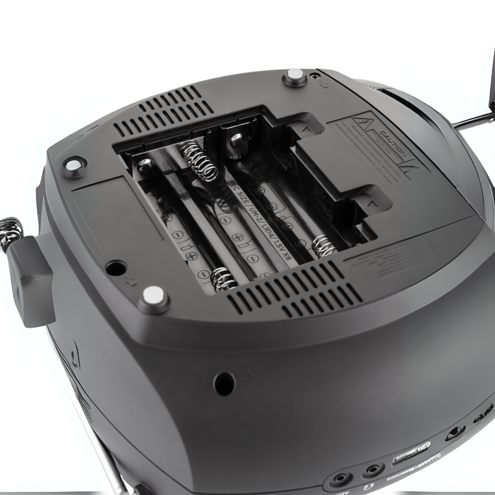 Zbliżenie ciemnoszarego radia z otwartą komorą baterii. Widoczne są cztery baterie. Z boku znajduje się etykieta ostrzegawcza.