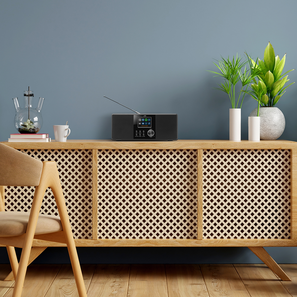 Nowoczesna scena w salonie z czarnym radiem na drewnianej szafce. Obecne są rośliny, krzesło i dekoracyjny szklany przedmiot.