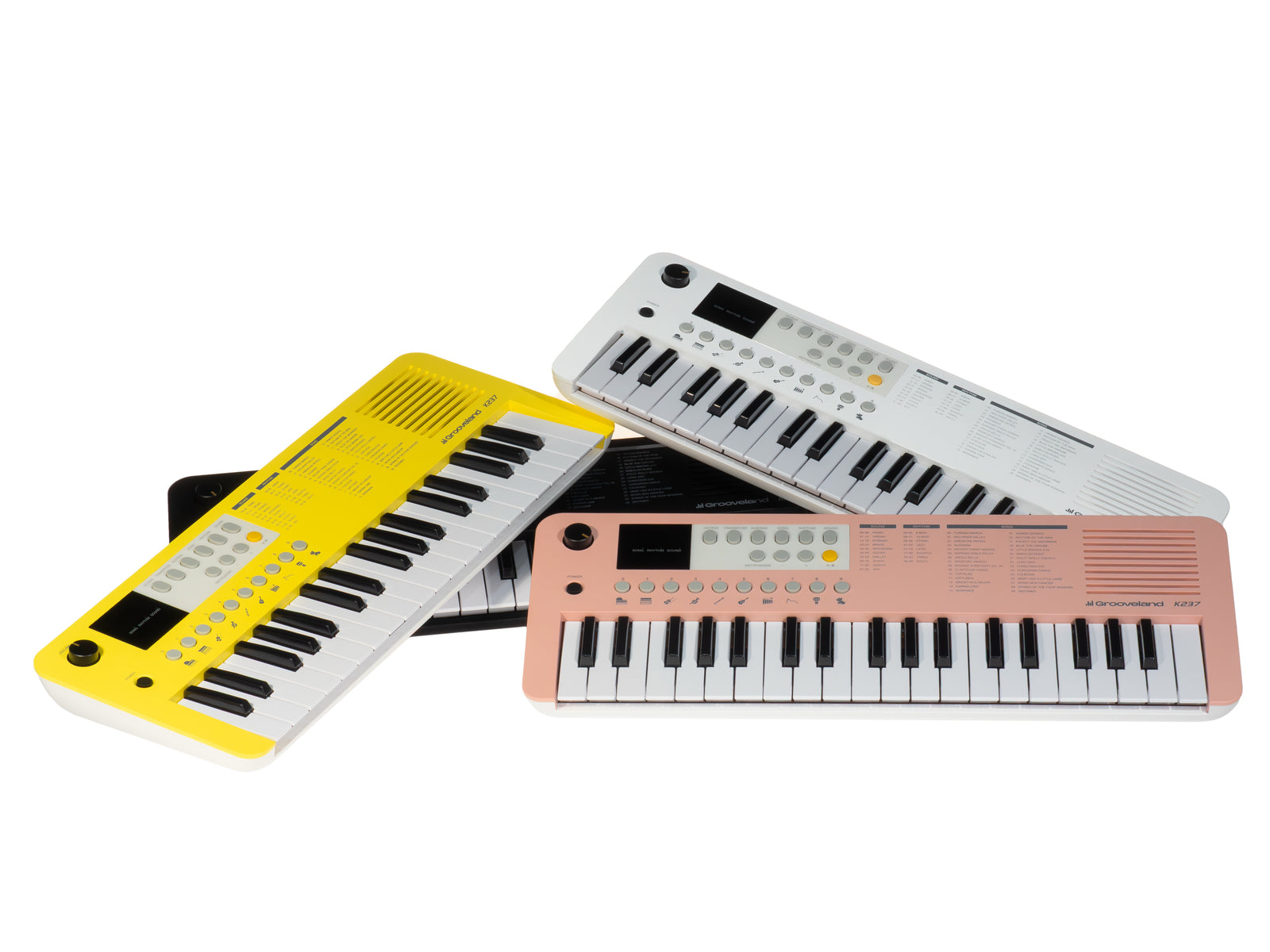 Drei Spielzeug-Keyboards in Gelb, Weiß, Rosa und Schwarz. Keyboards sind abgewinkelt. Weißer Hintergrund.