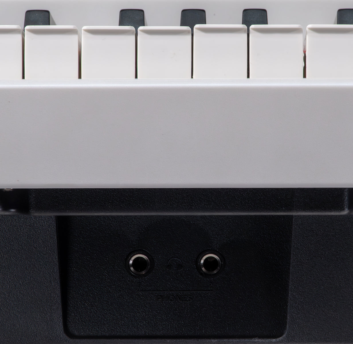 Nahaufnahme einer Tastatur mit weißen Tasten und schwarzen Akzenten. Darunter befinden sich zwei Kopfhöreranschlüsse auf schwarzem Untergrund.