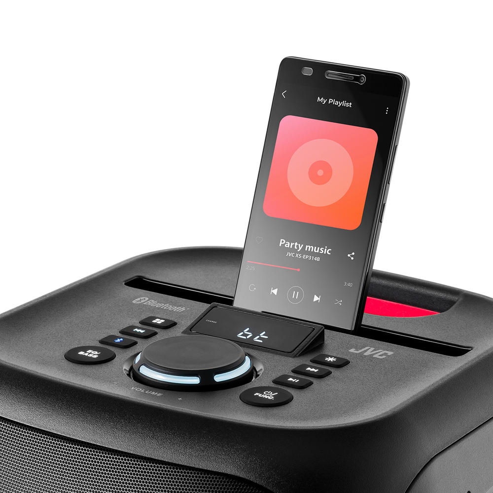 Smartfon odtwarzający muzykę jest zadokowany w czarnym głośniku. Ekran wyświetla aplikację muzyczną z utworem muzyki imprezowej.