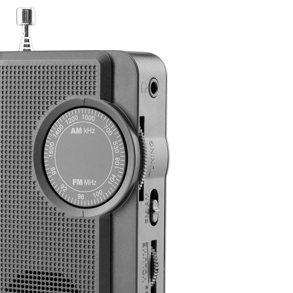 Zbliżenie szarego radia. Radio ma pokrętło strojenia, przełącznik głośności i FM/AM. Widoczne jest gniazdo słuchawkowe. Antena jest wysunięta.