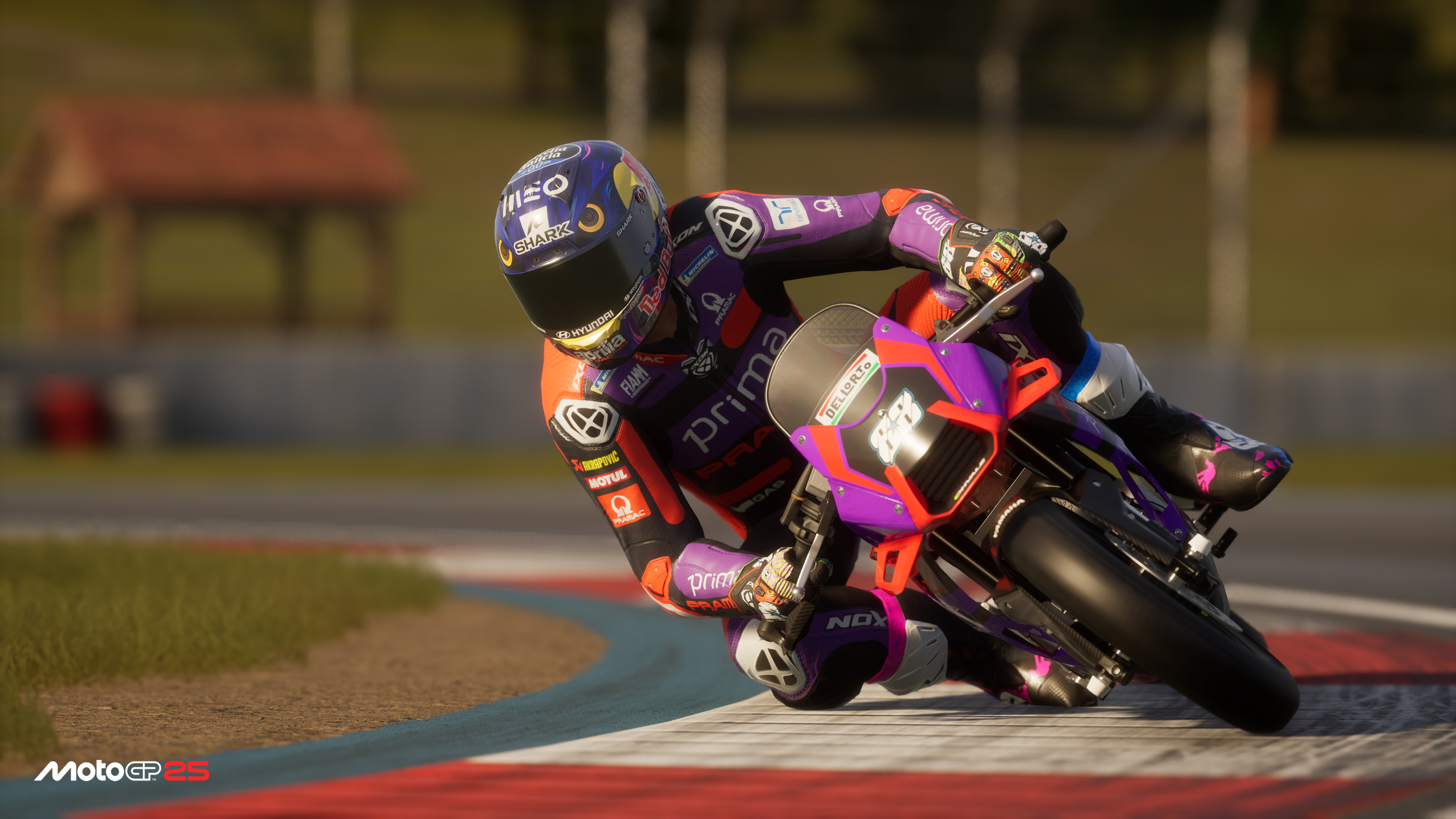 Un pilota di moto si piega in una curva. La moto è viola e nera. Il pilota indossa una tuta viola, arancione e nera e un casco.