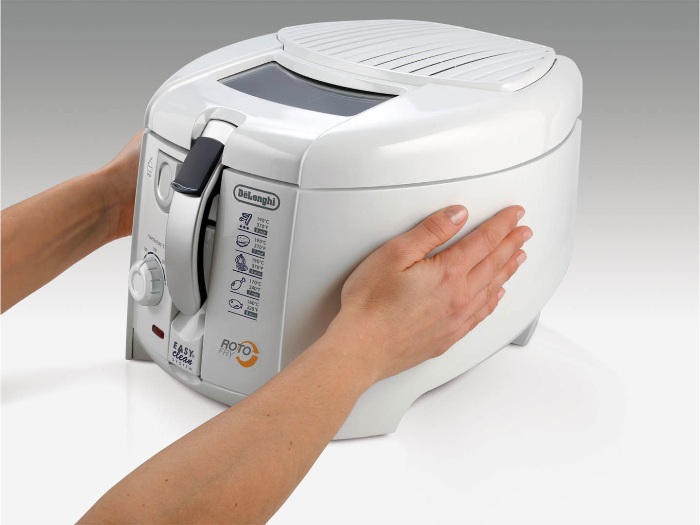 Una persona tiene in mano una friggitrice Roto DeLonghi bianca. La friggitrice ha coperchio, maniglia e comandi della temperatura. Mani su entrambi i lati.