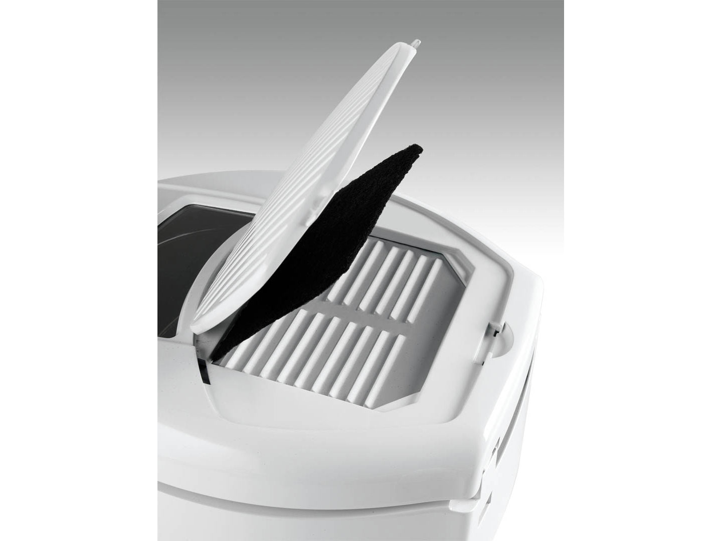 Un elettrodomestico bianco con coperchio aperto. Un filtro nero è visibile. L'apparecchio ha una superficie a coste, con un design semplice.