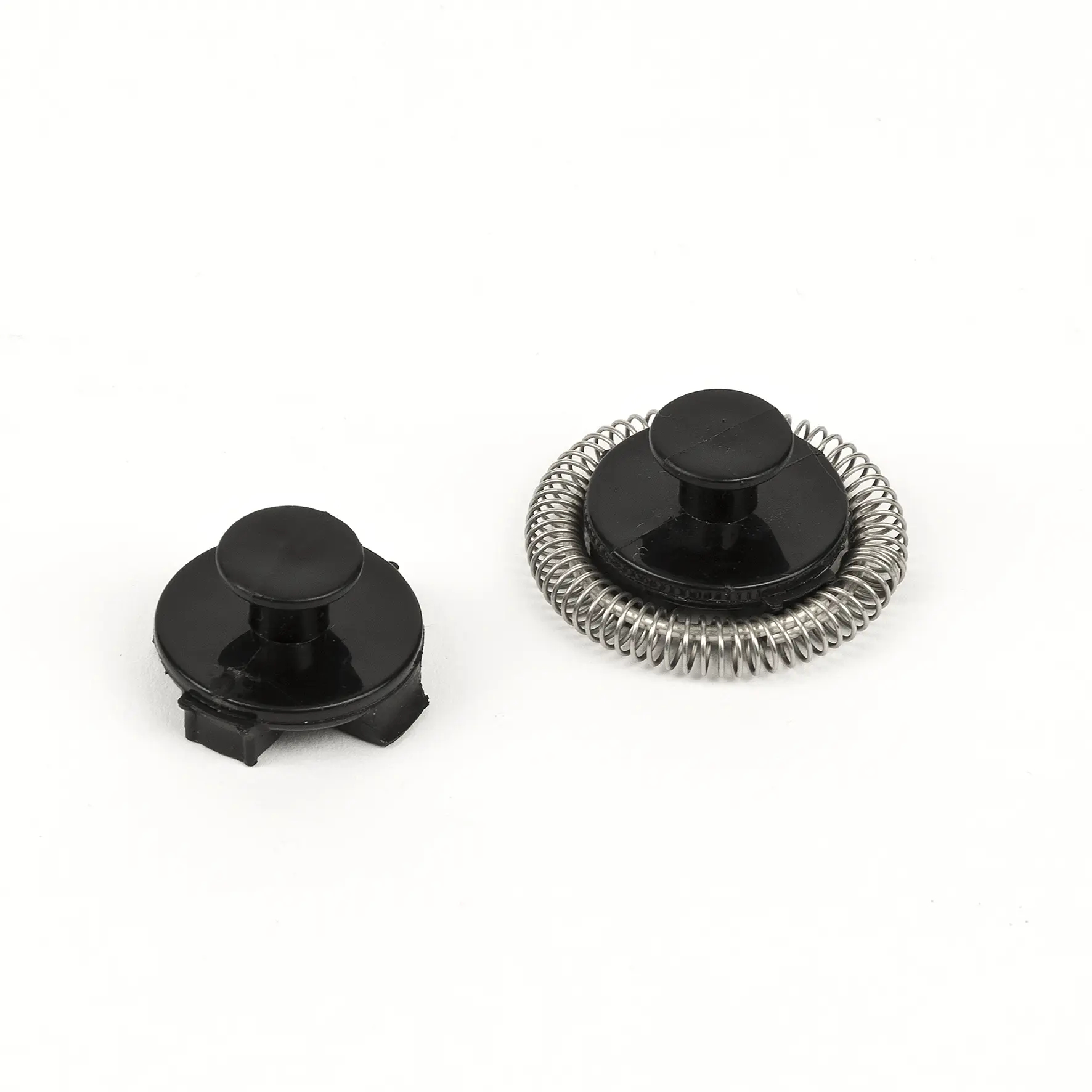 Dwa czarne nasadki do spieniania na białej powierzchni. Jedna ze sprężyną, druga bez.