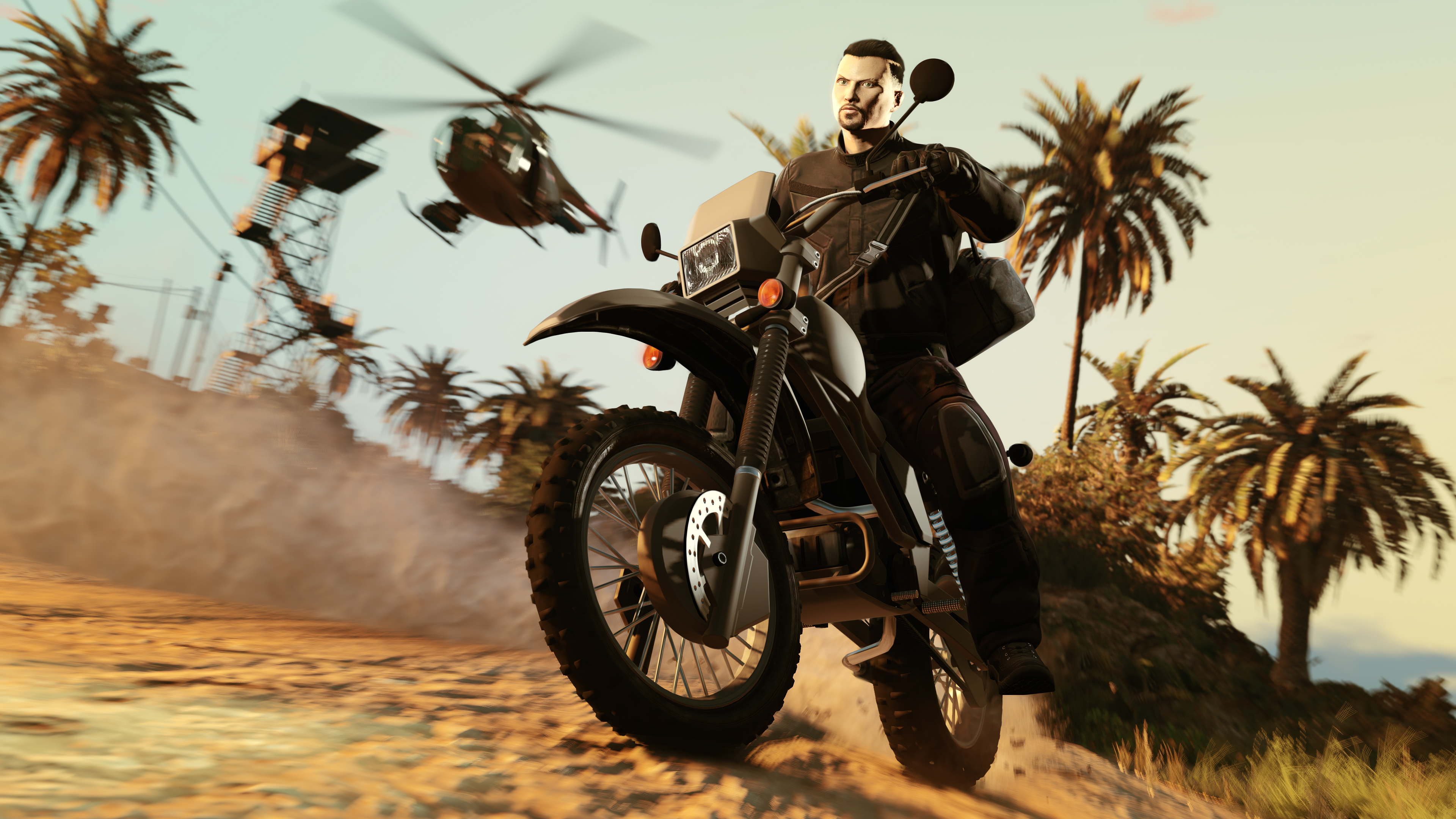 Hombre montando una moto negra en un camino de tierra. Un helicóptero y una torre al fondo, palmeras a los lados.