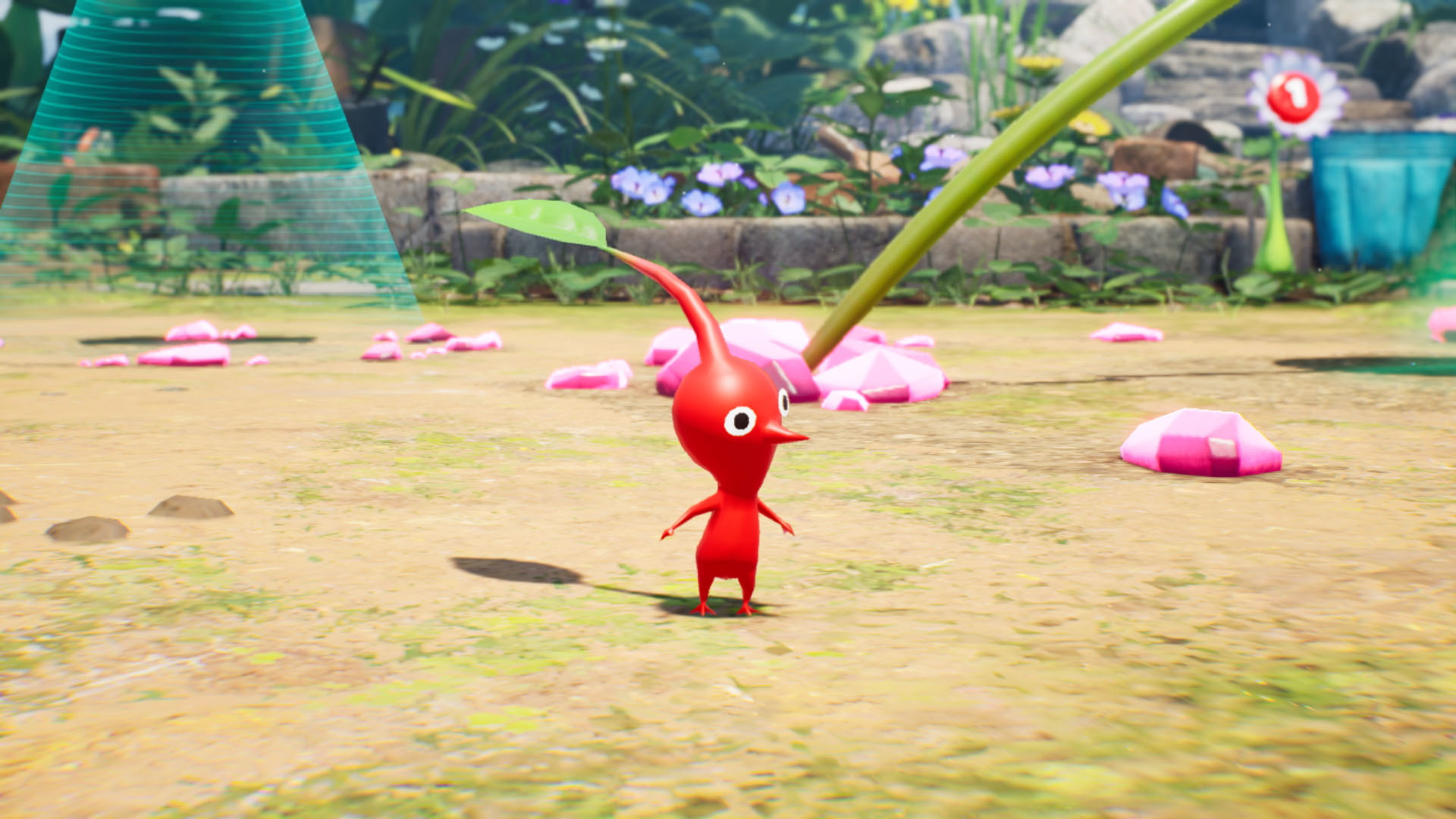Ein rotes Pikmin steht auf dem Boden, mit einem Blatt auf dem Kopf. Rosa Objekte sind verstreut. Grüne Pflanzen und Blumen sind im Hintergrund.