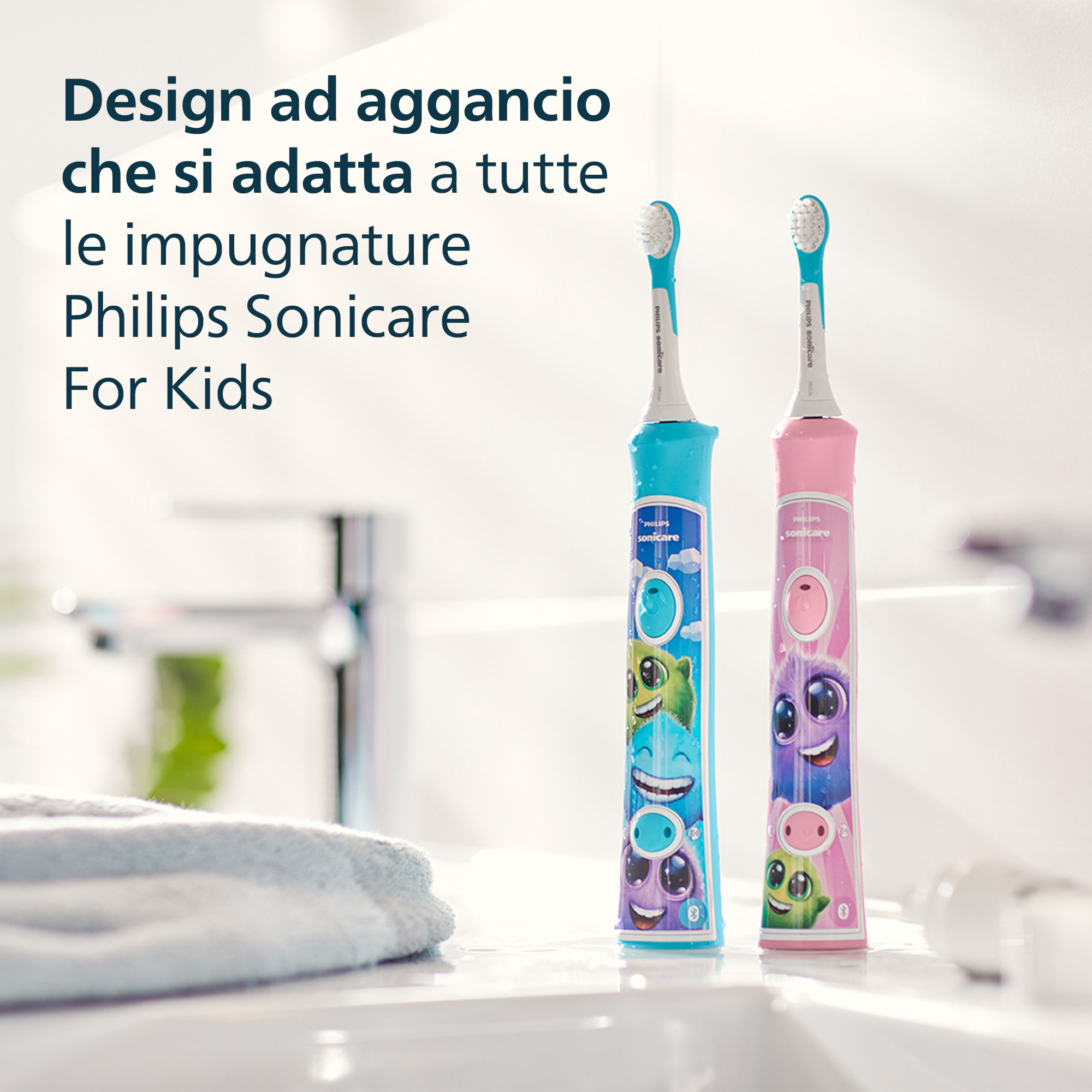 Zwei Philips Sonicare For Kids Zahnbürsten, blau und rosa, auf einer Badezimmerablage. Ein Handtuch ist in der Nähe.