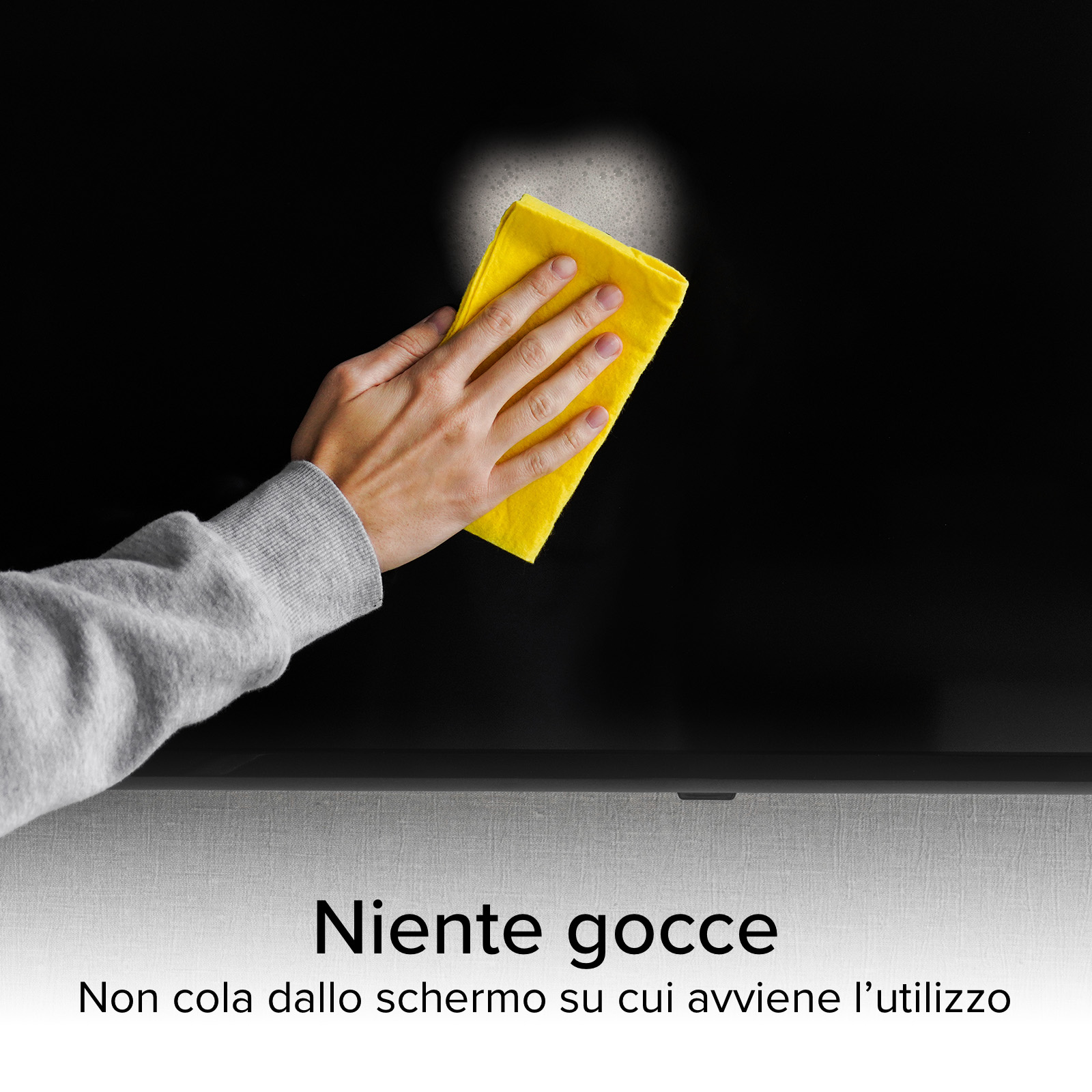 Una mano pulisce uno schermo nero con un panno giallo. Il panno è bagnato. Il testo dice 'Niente gocce'.