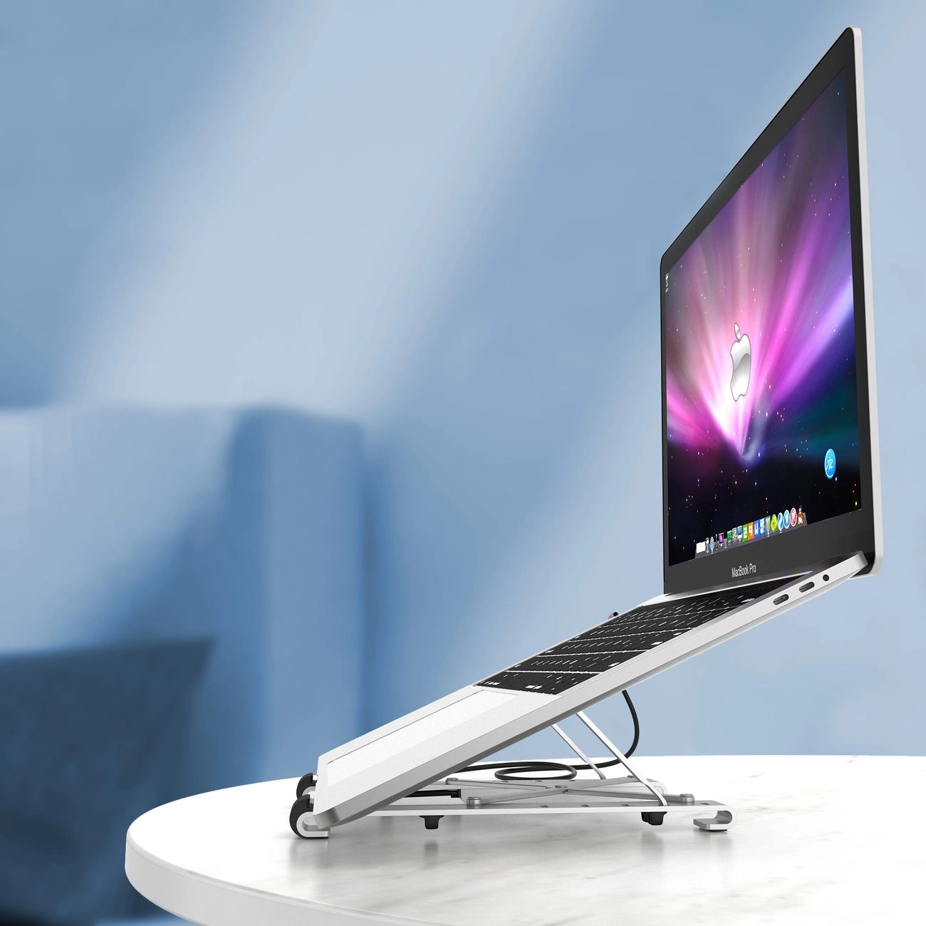 Ein Macbook Pro Laptop auf einem weißen Ständer. Der Bildschirm zeigt einen bunten Hintergrund. Der Laptop steht auf einem weißen Tisch mit blauem Hintergrund.