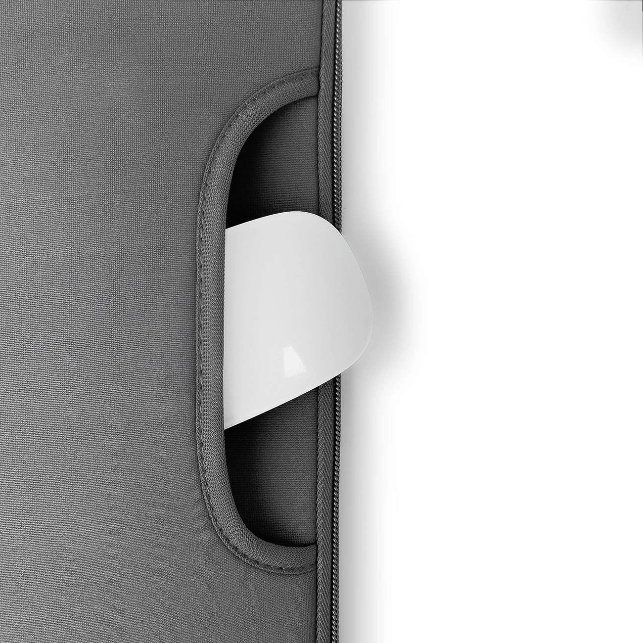 Eine weiße Computermaus, die teilweise in eine graue Laptoptaschen-Tasche gesteckt ist. Die Hülle ist links, weißer Hintergrund rechts.