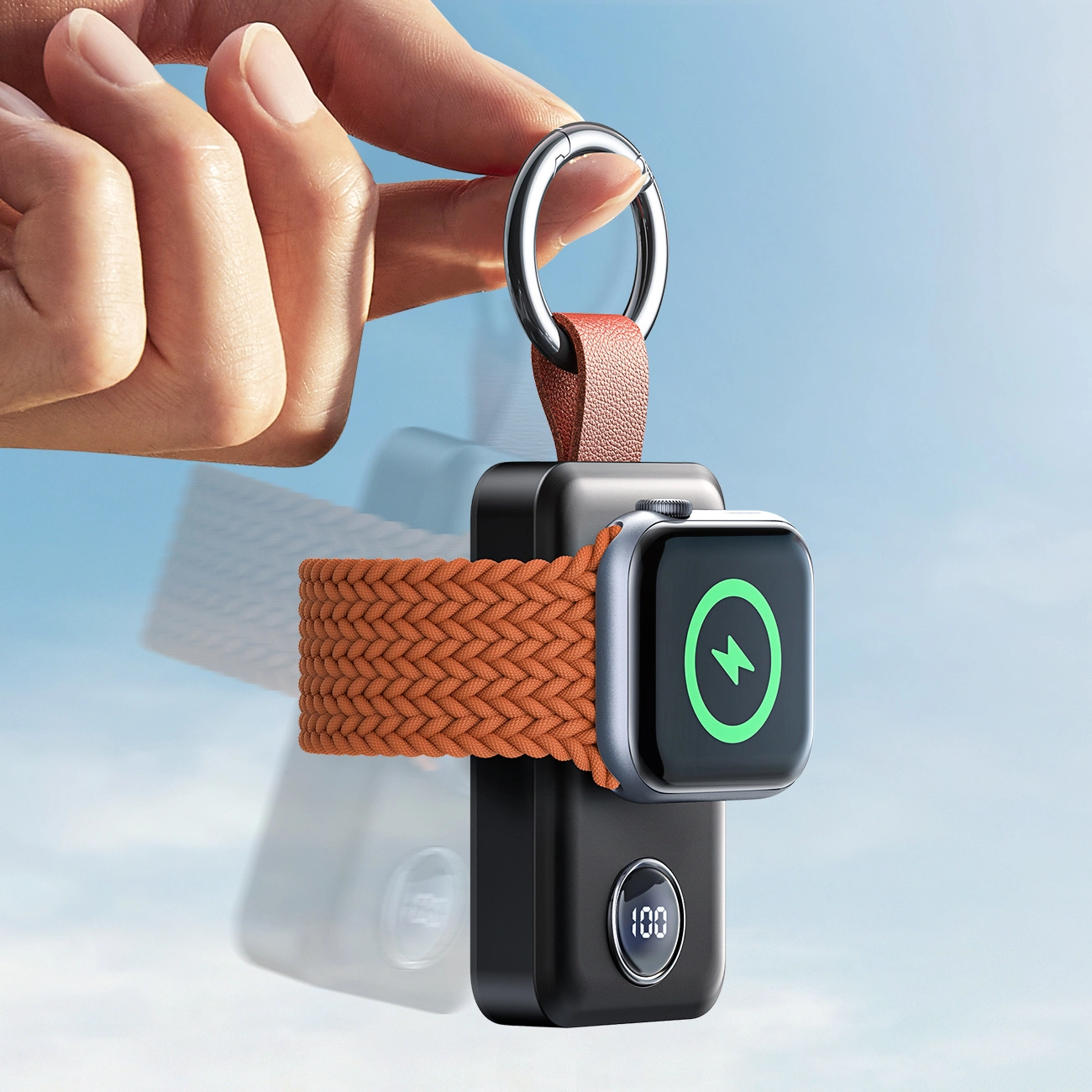 Eine Hand hält ein Ladegerät mit einer Apple Watch. Das Ladegerät ist schwarz mit einem orangenen Band. Das Uhrenbild zeigt einen grünen Blitz.
