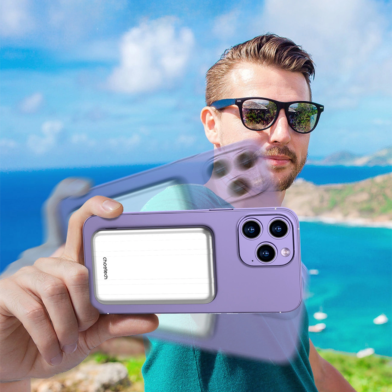 Mann mit Sonnenbrille hält eine Handyhülle, lila Farbe. Hintergrund zeigt Meer und blauen Himmel.