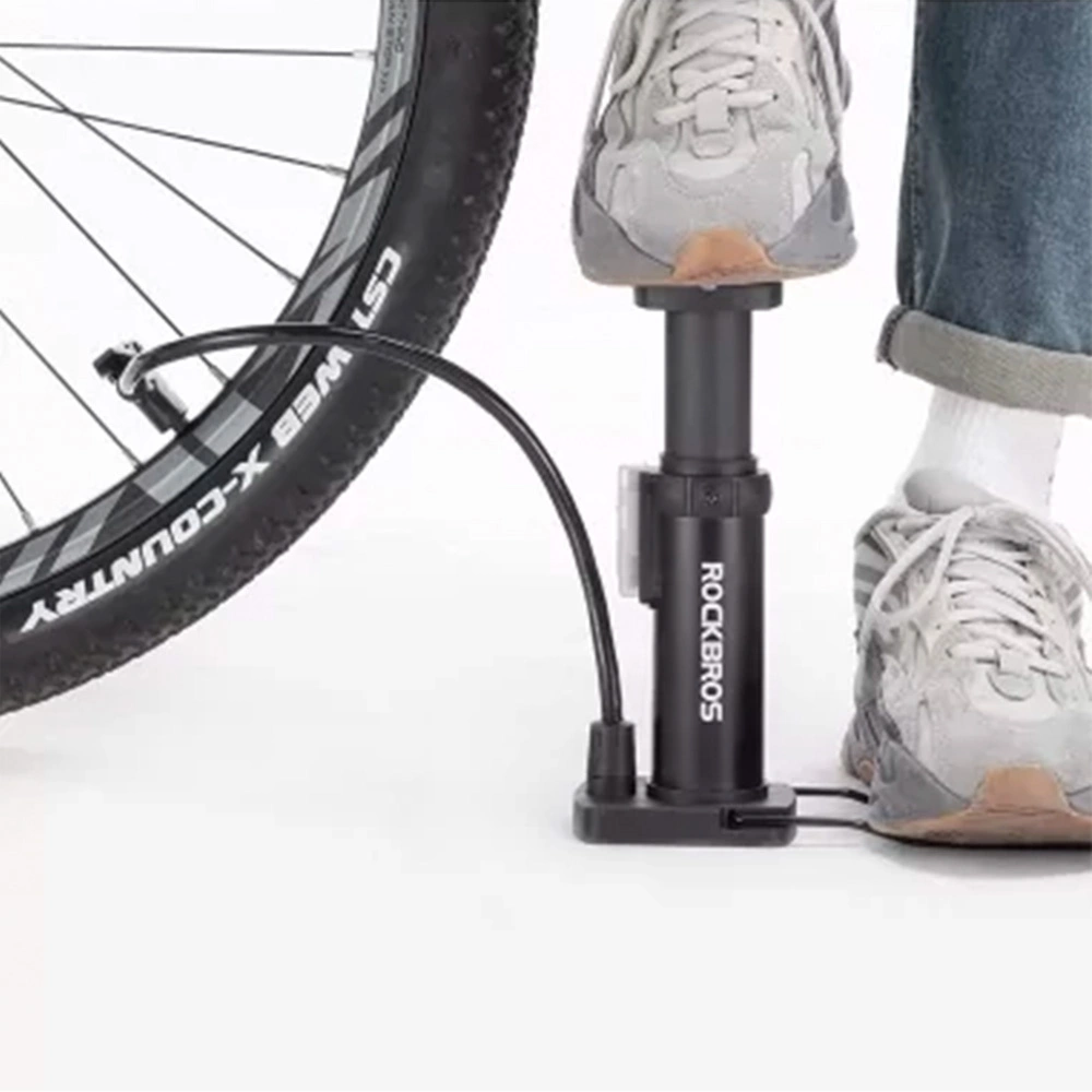 Una persona gonfia uno pneumatico di bicicletta con una pompa a pedale. Lo pneumatico è nero e la pompa è nera con il marchio ROCKBROS.