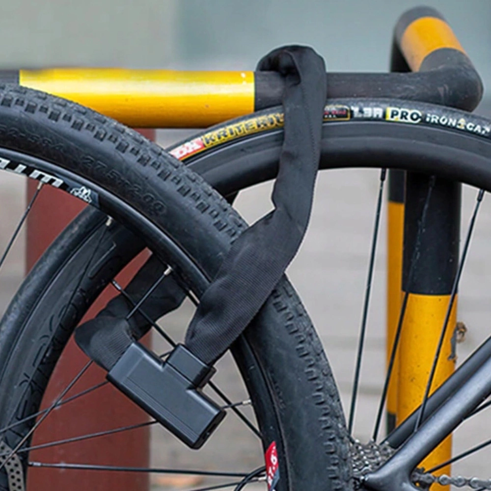 Un lucchetto a catena nero assicura la ruota di una bicicletta a un palo giallo e nero. Il pneumatico è nero.