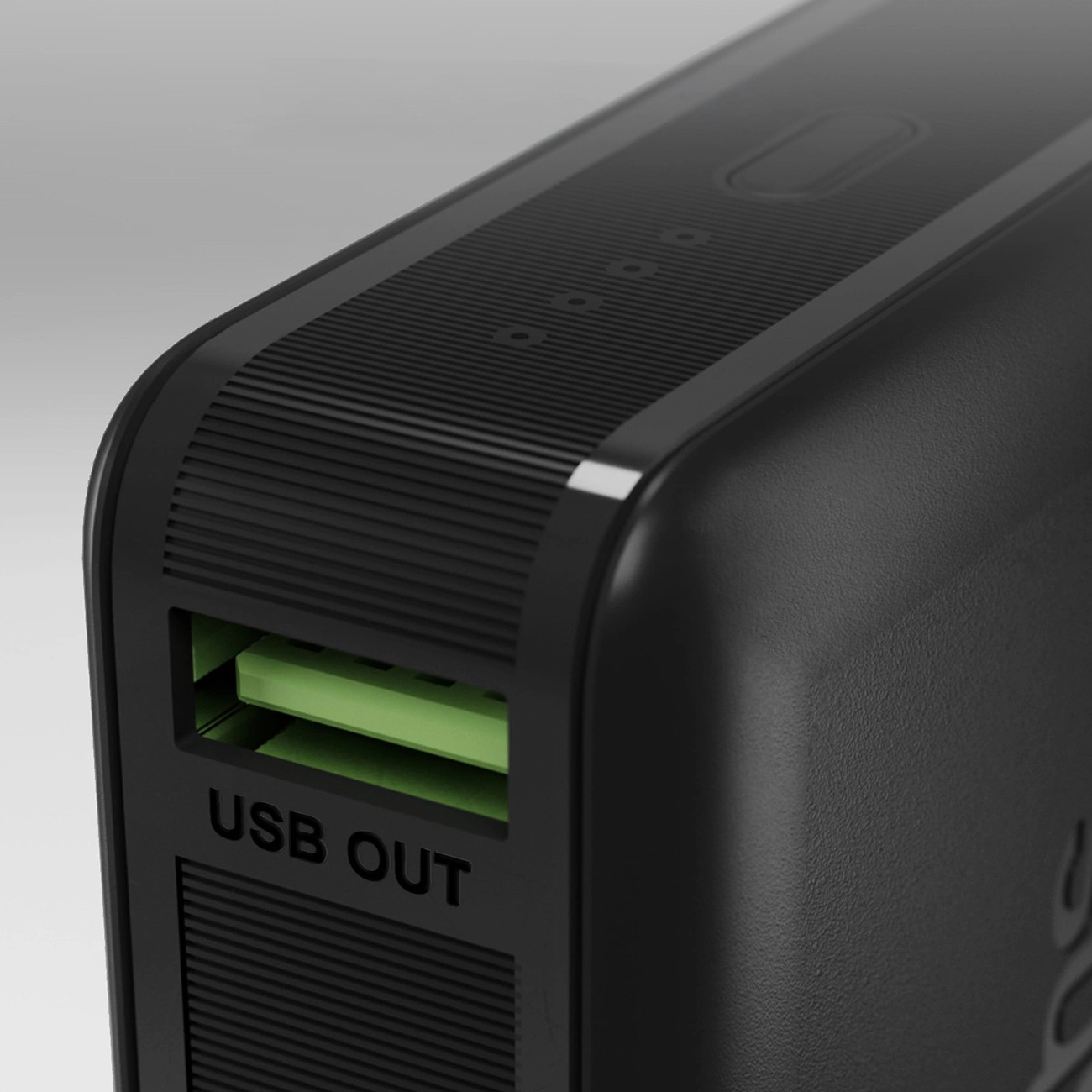 Zbliżenie czarnego power banku z zielonym portem USB. Widoczne są słowa 'USB OUT'. Na górze znajdują się małe przyciski.
