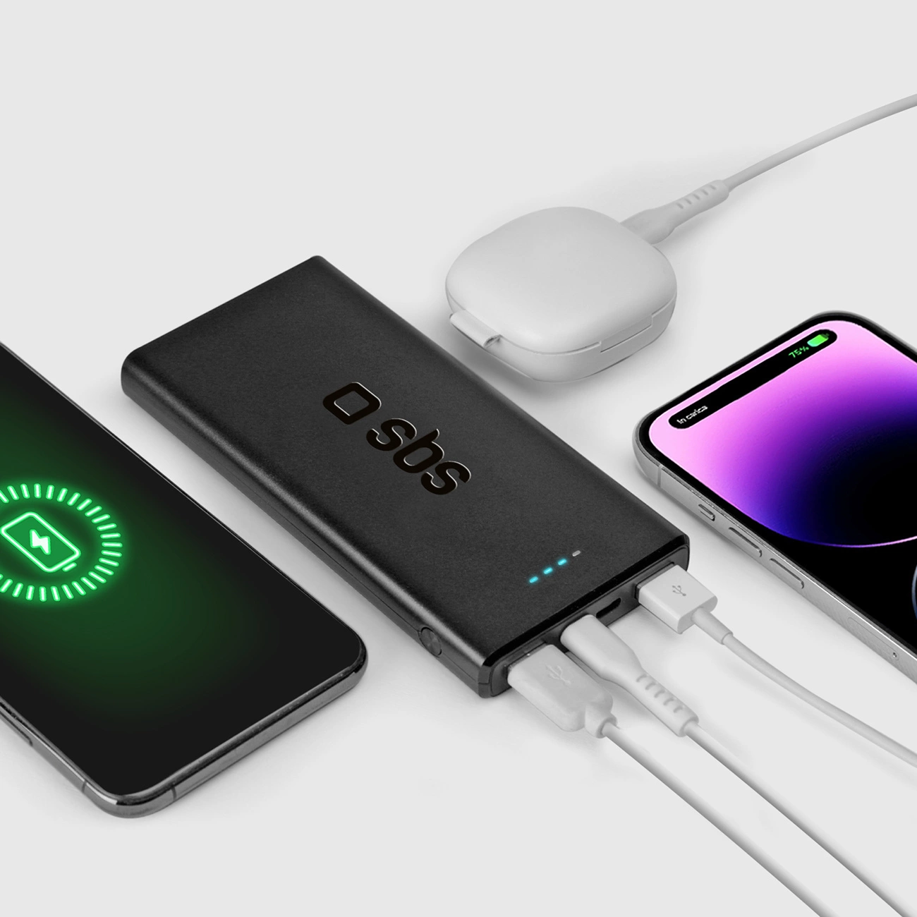 Power bank nera con due telefoni in carica, una custodia di ricarica bianca e cavi su una superficie bianca.