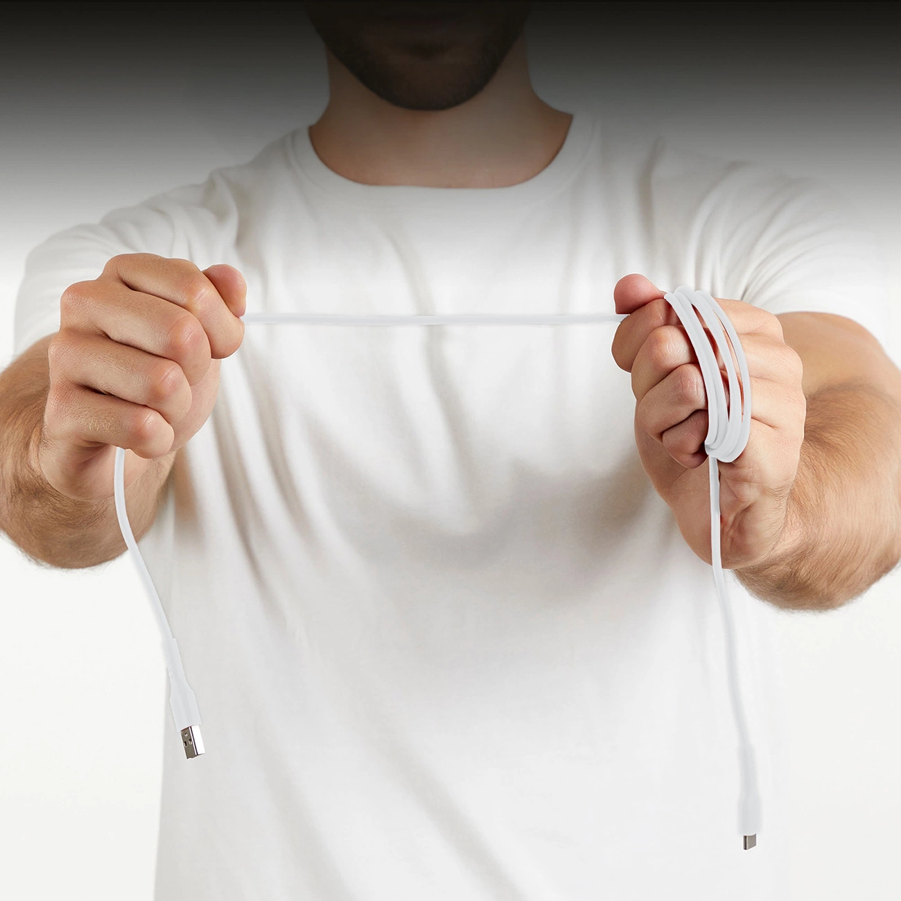 Un uomo con una camicia bianca tiene in mano un cavo bianco. Un'estremità è dritta, l'altra è arrotolata.