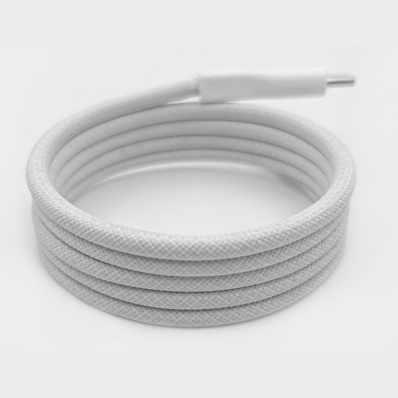 Un cavo USB-C bianco arrotolato su una superficie bianca. Il cavo ha una trama simile al tessuto e un connettore a un'estremità.