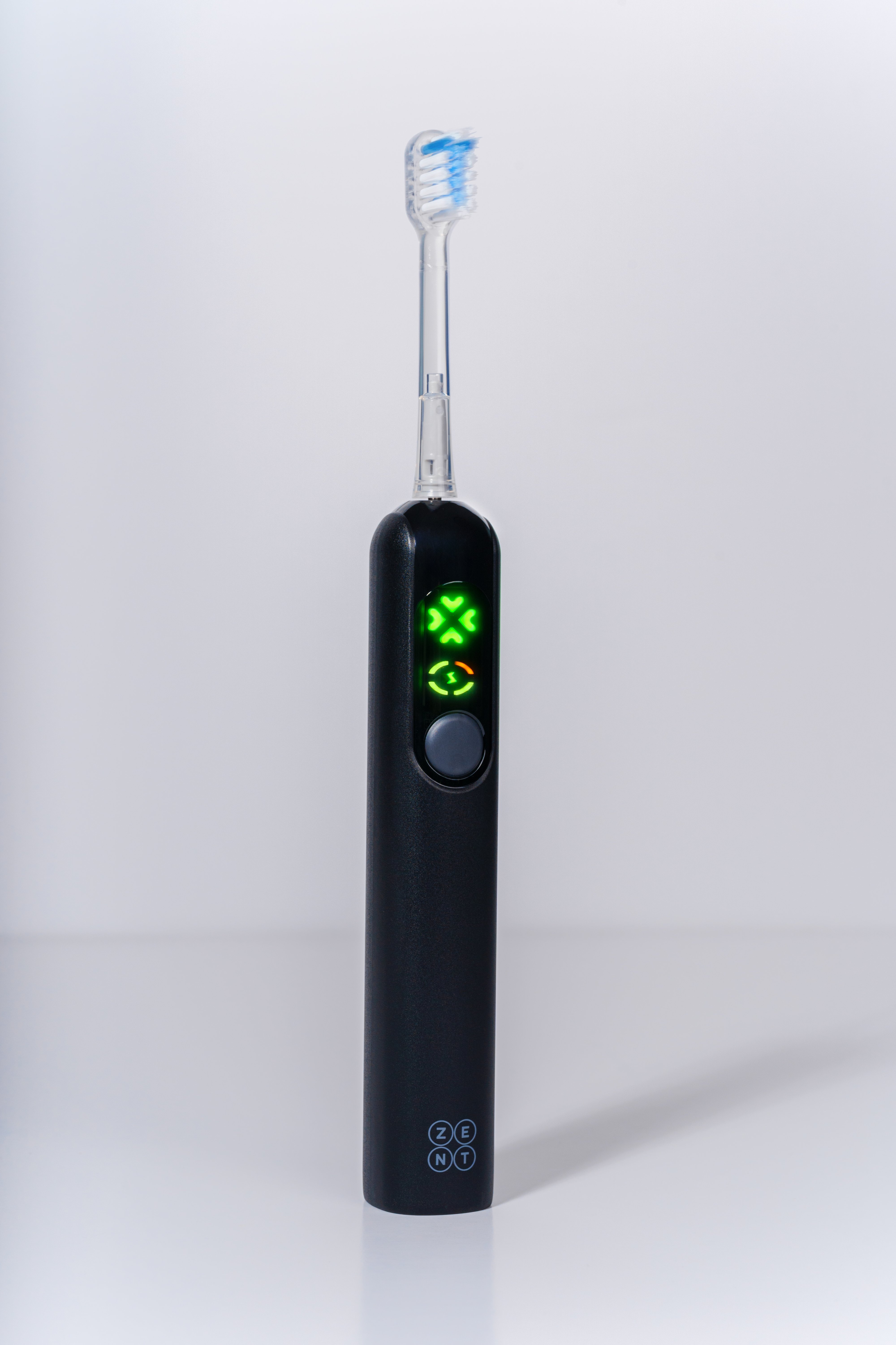 Czarna elektryczna szczoteczka do zębów z niebieskim włosiem na białym tle. Zielone światła wskazują tryb. Marka: ZENT.