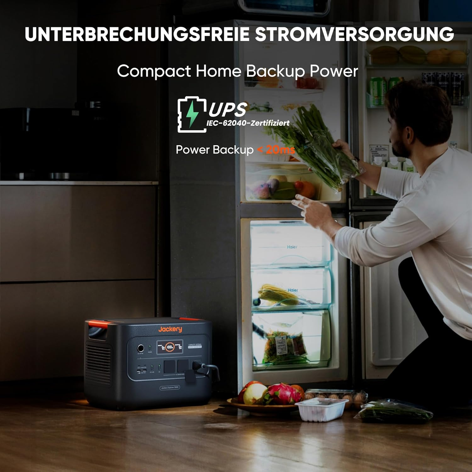 Ein Mann steht an einem offenen Kühlschrank und hält Gemüse. Eine Jackery-Powerstation steht auf dem Boden. Text: 'Compact Home Backup Power'.