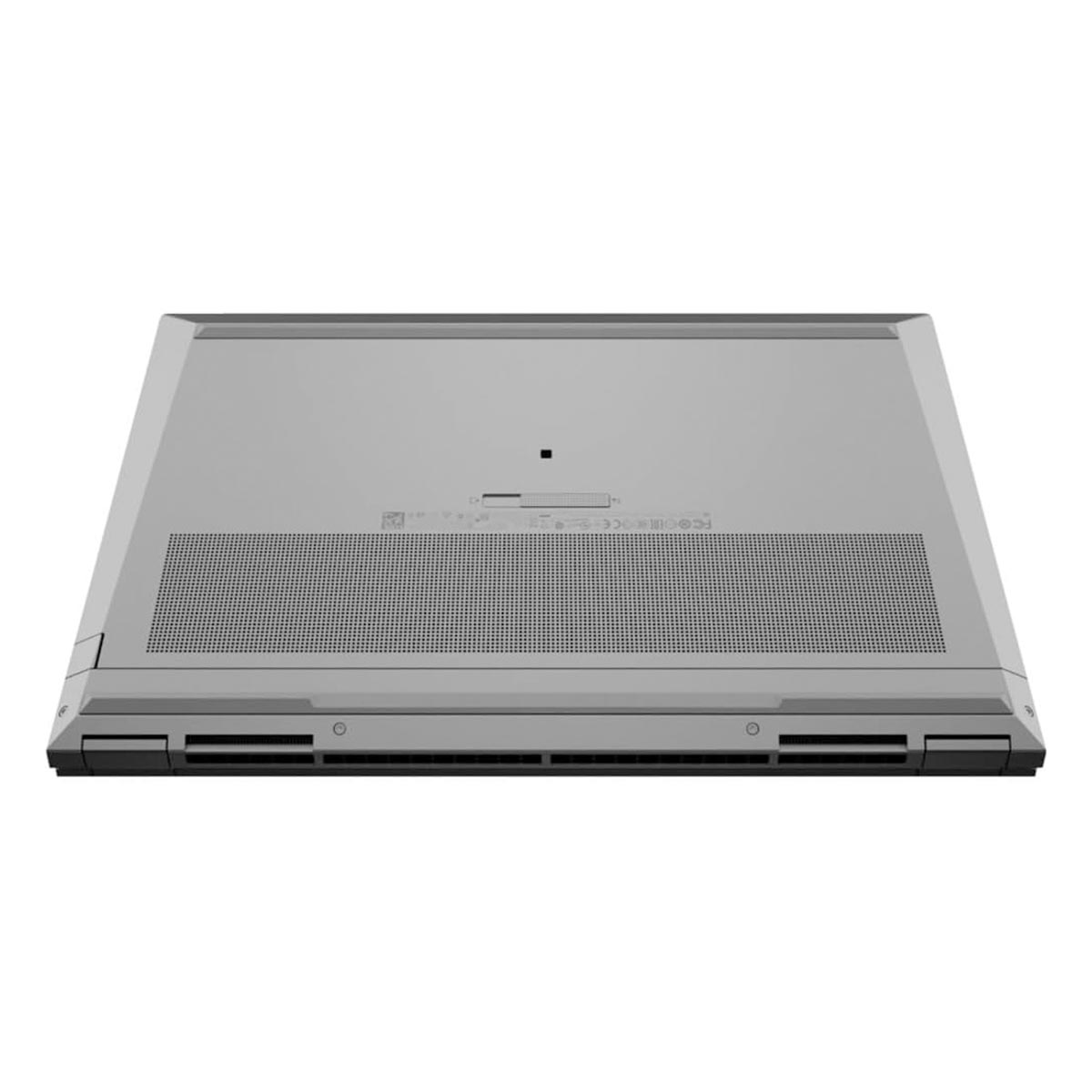 Widoczna jest dolna strona szarego laptopa. Ma perforowaną sekcję, otwory wentylacyjne i kilka małych śrub.