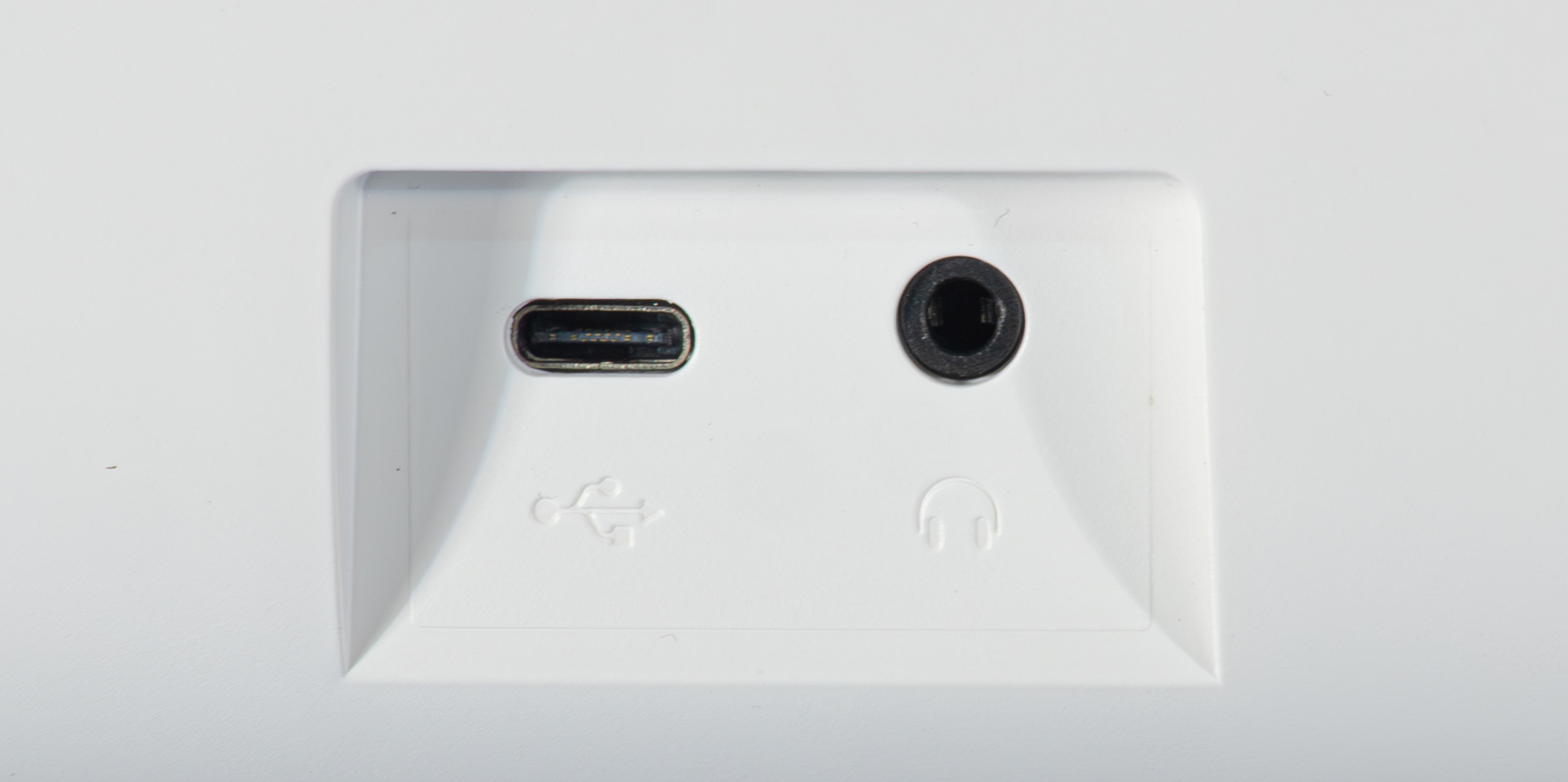 Ein weißes Panel mit einem USB-C-Anschluss, einer Kopfhörerbuchse, einem USB-Symbol und einem Kopfhörersymbol.