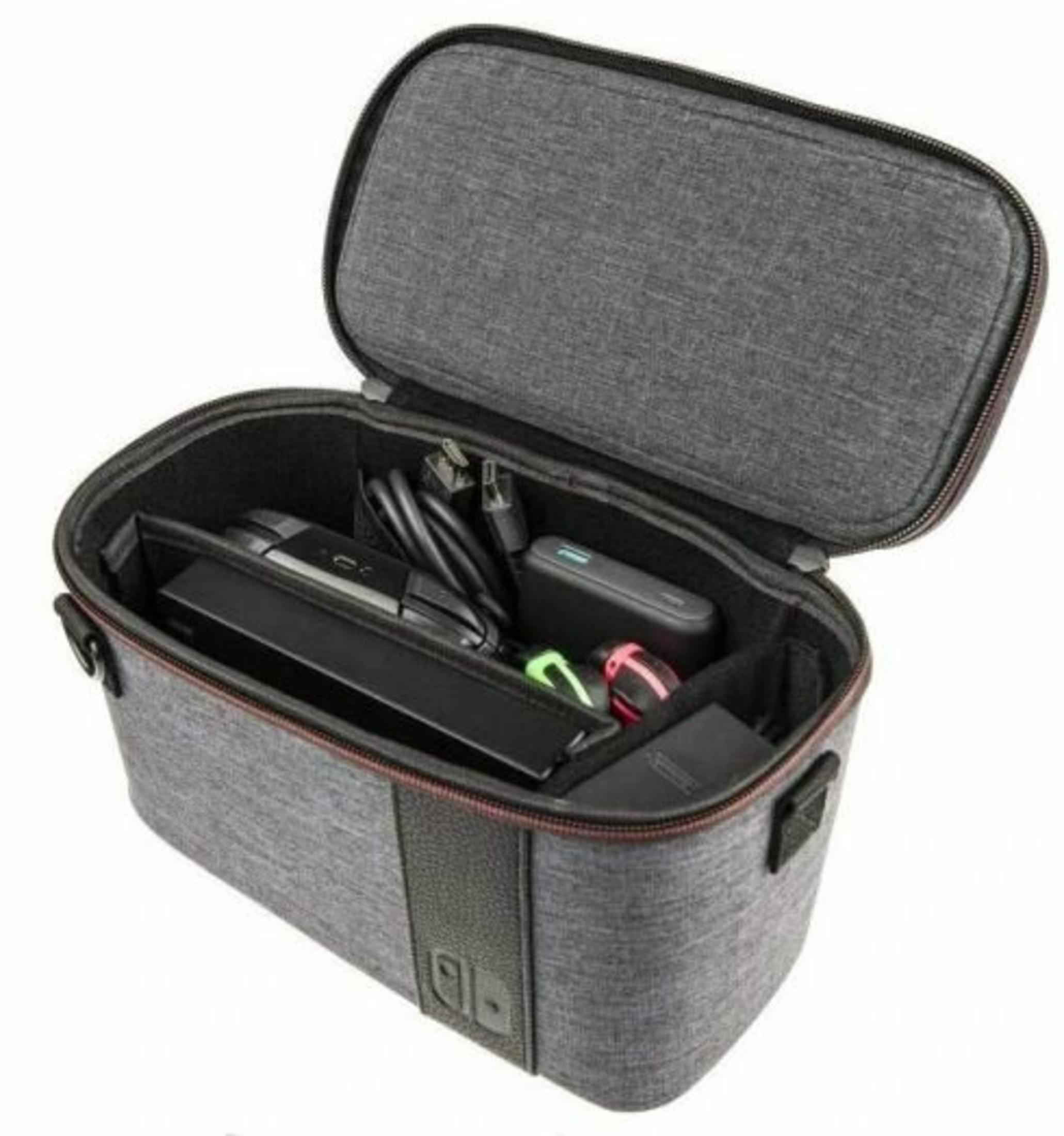 Offene graue Tasche mit schwarzem Innenraum. Enthält eine Spielkonsole, Ladegerät, Kabel und Zubehör. Schwarzer Griff.