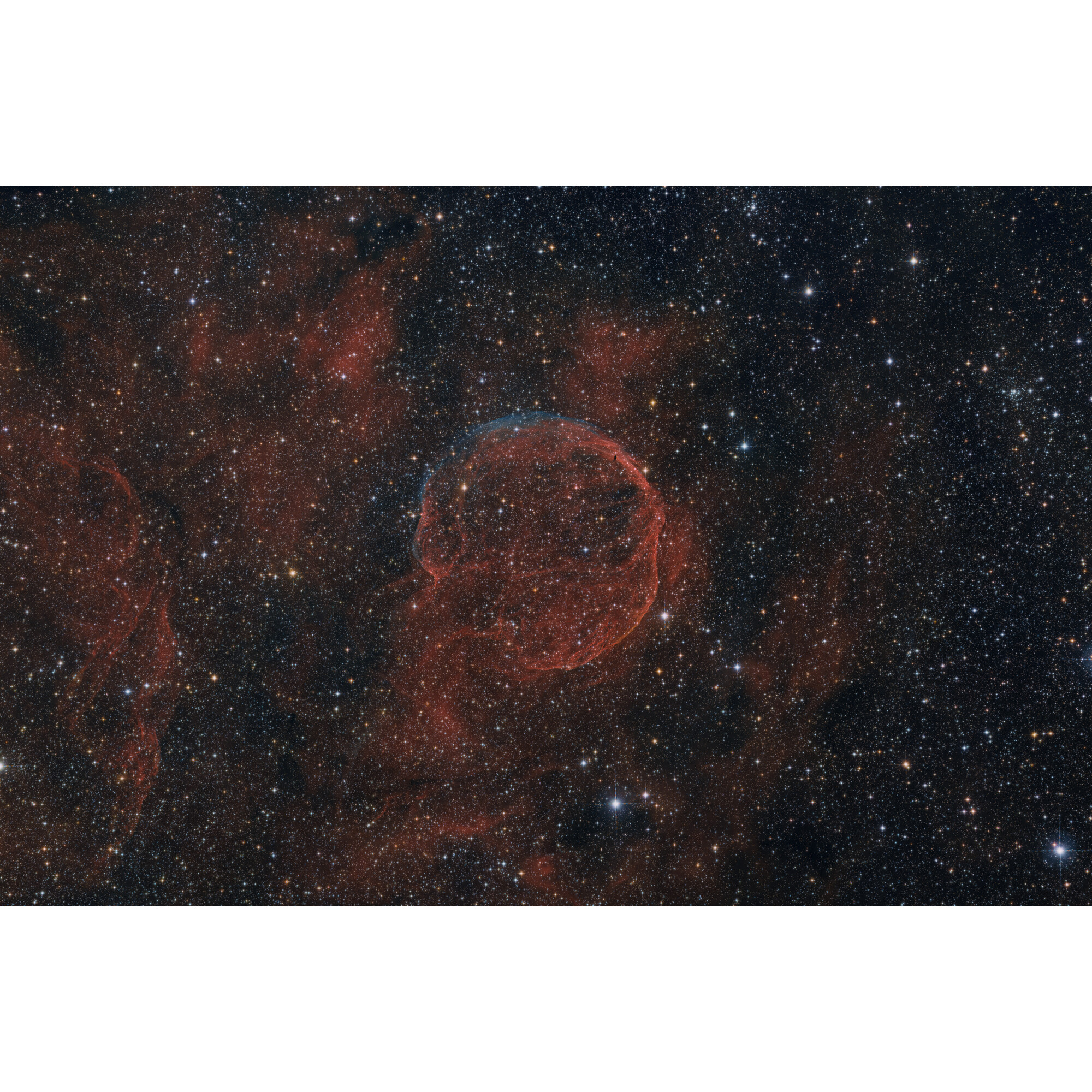 Ein kosmische Bild zeigt einen roten Nebel mit einem blauen Ring, umgeben von unzähligen Sternen im dunklen Weltall.