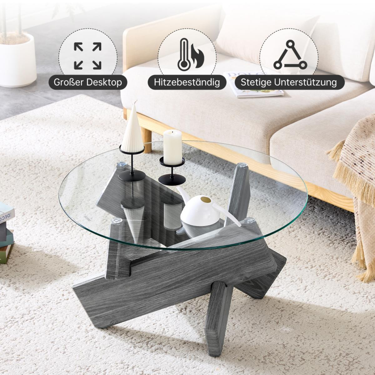 Ein moderner Couchtisch mit Glasplatte und grauen Holzstützen. Zwei Kerzen und eine weiße Gießkanne stehen auf dem Tisch. Im Hintergrund ist ein Sofa.
