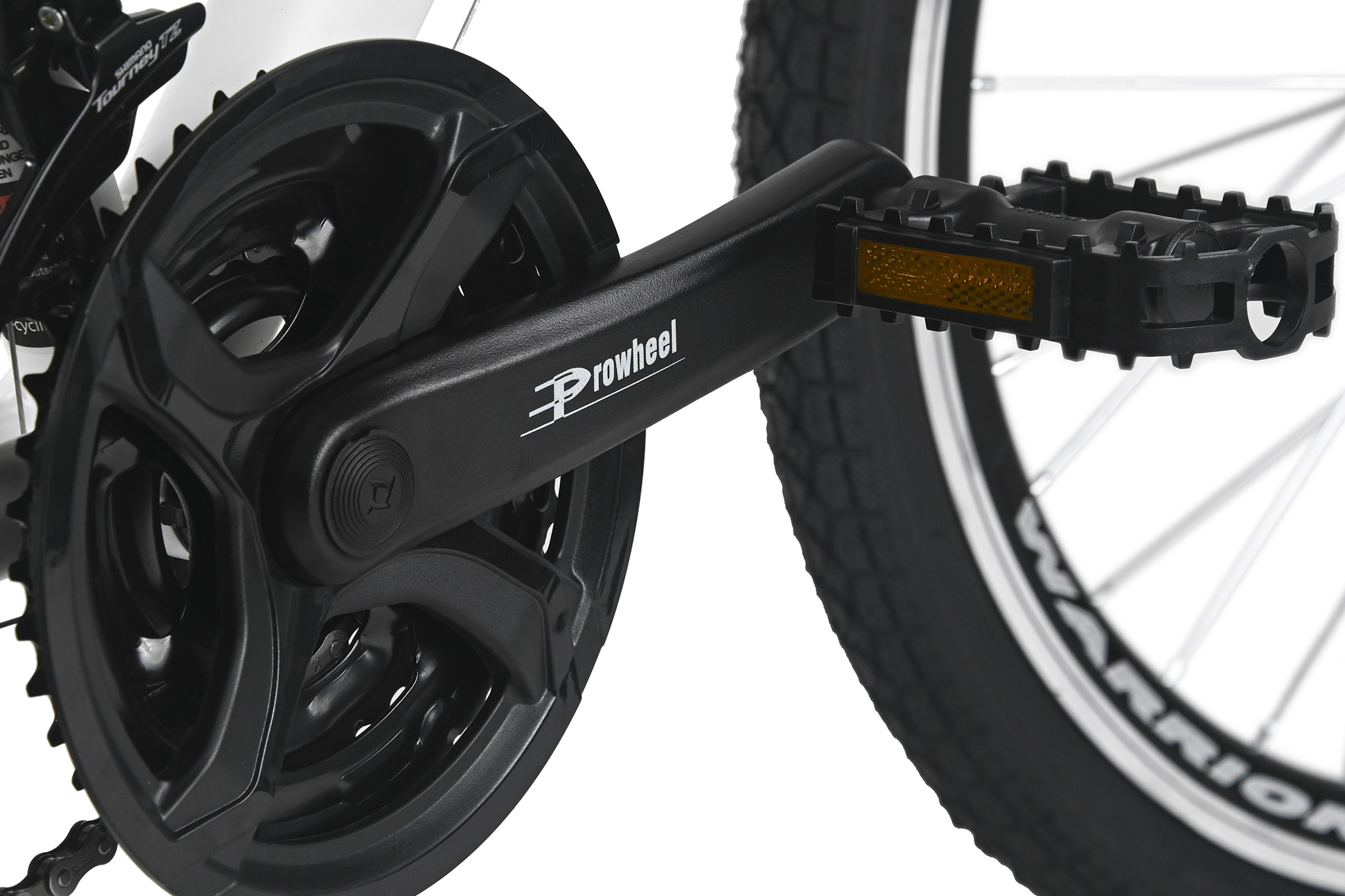 Nahaufnahme von Fahrradkurbel, Pedal und Reifen. Das Pedal hat einen Reflektor. Das Rad hat einen 'Warrior'-Aufkleber.