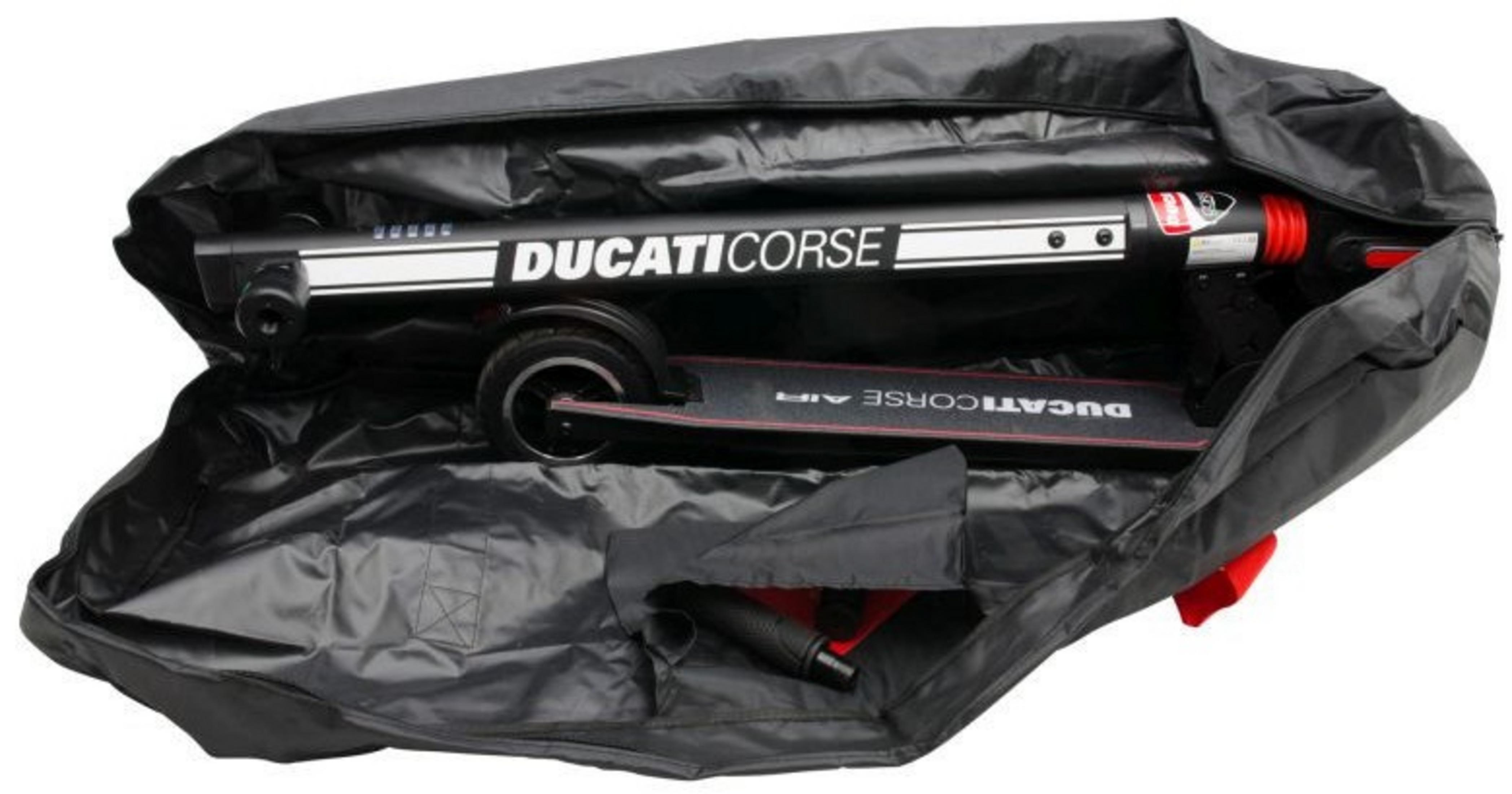 A black scooter with white lettering 'DUCATICORSE' is inside a black bag. The bag is open, showing the scooter parts.