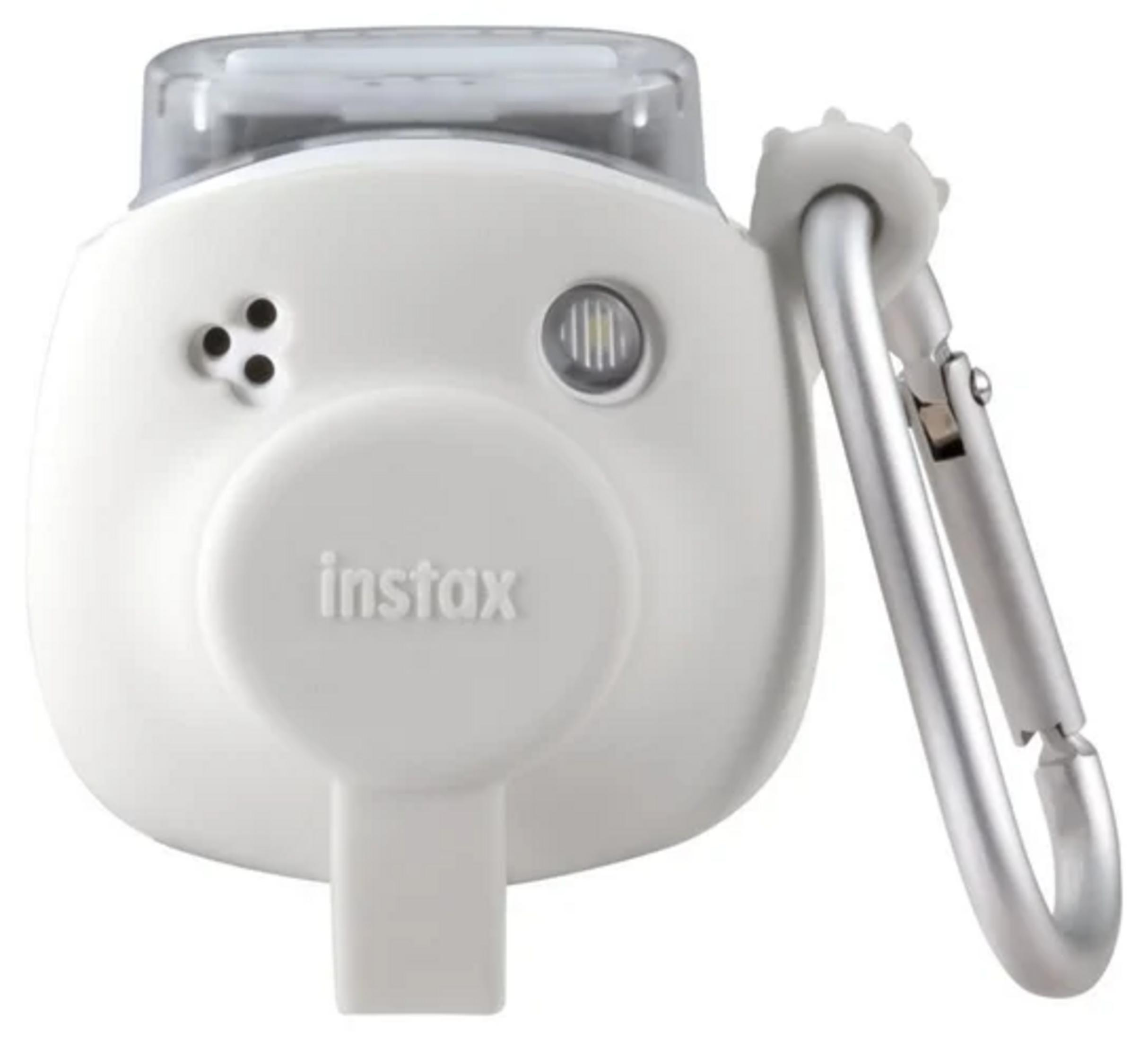 Un appareil photo Instax blanc avec un mousqueton argenté. Il a un dessus transparent et le logo Instax.