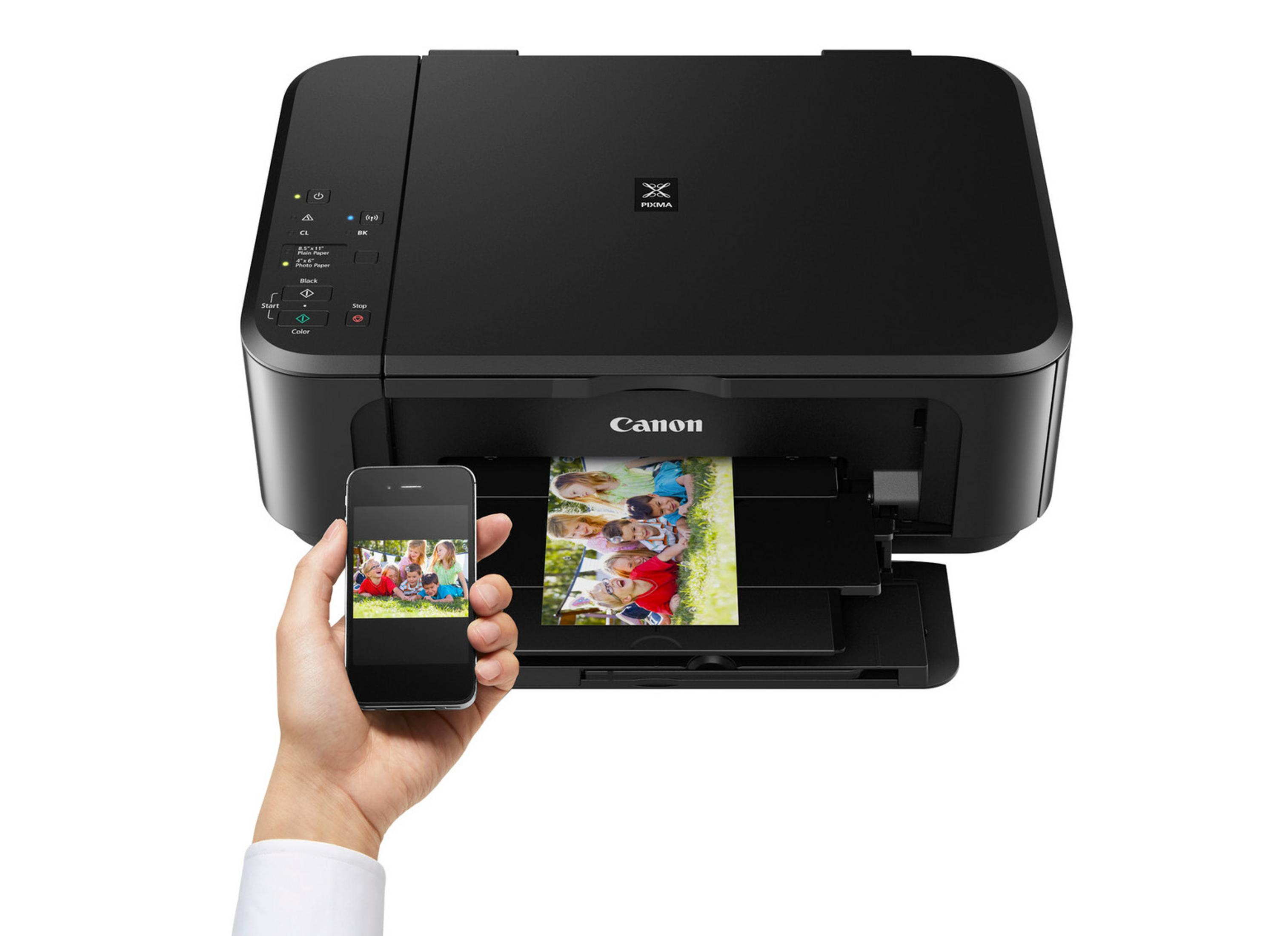 Czarna drukarka Canon drukuje zdjęcie. Ręka trzyma telefon z podobnym obrazem.