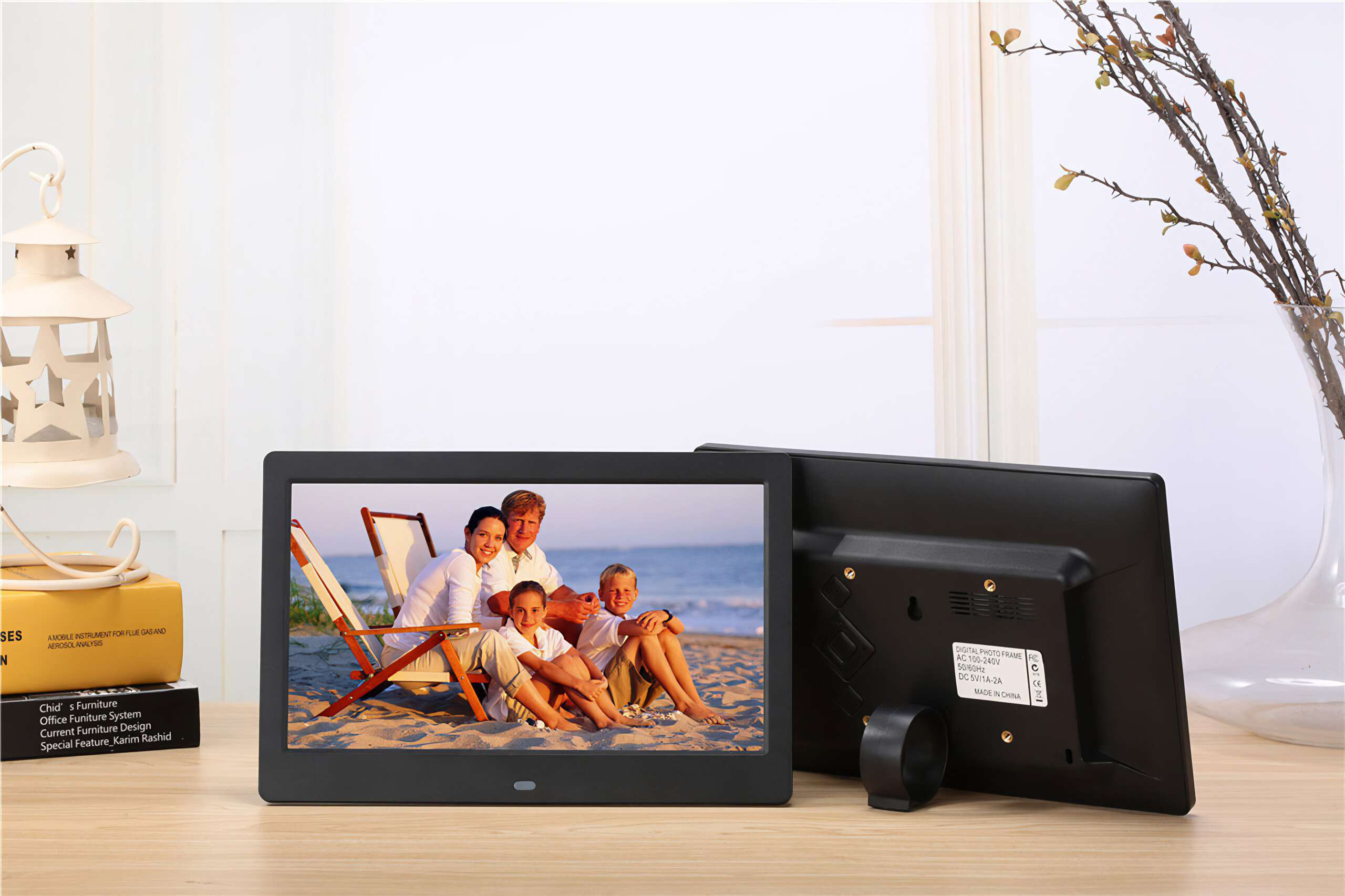 Digitaler Fotorahmen zeigt eine Familie am Strand. Dahinter steht ein weiterer Rahmen. Eine Vase und Dekoration sind sichtbar.