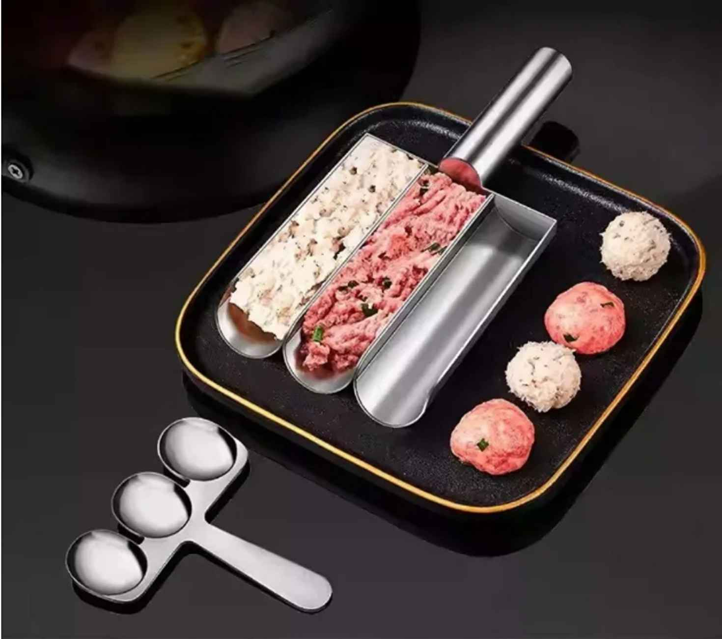 Ein Fleischbällchenmacher mit rohem Fleisch und geformten Fleischbällchen. Beinhaltet ein Werkzeug mit drei Schöpflöffeln und einem Tablett mit drei Schlitzen.