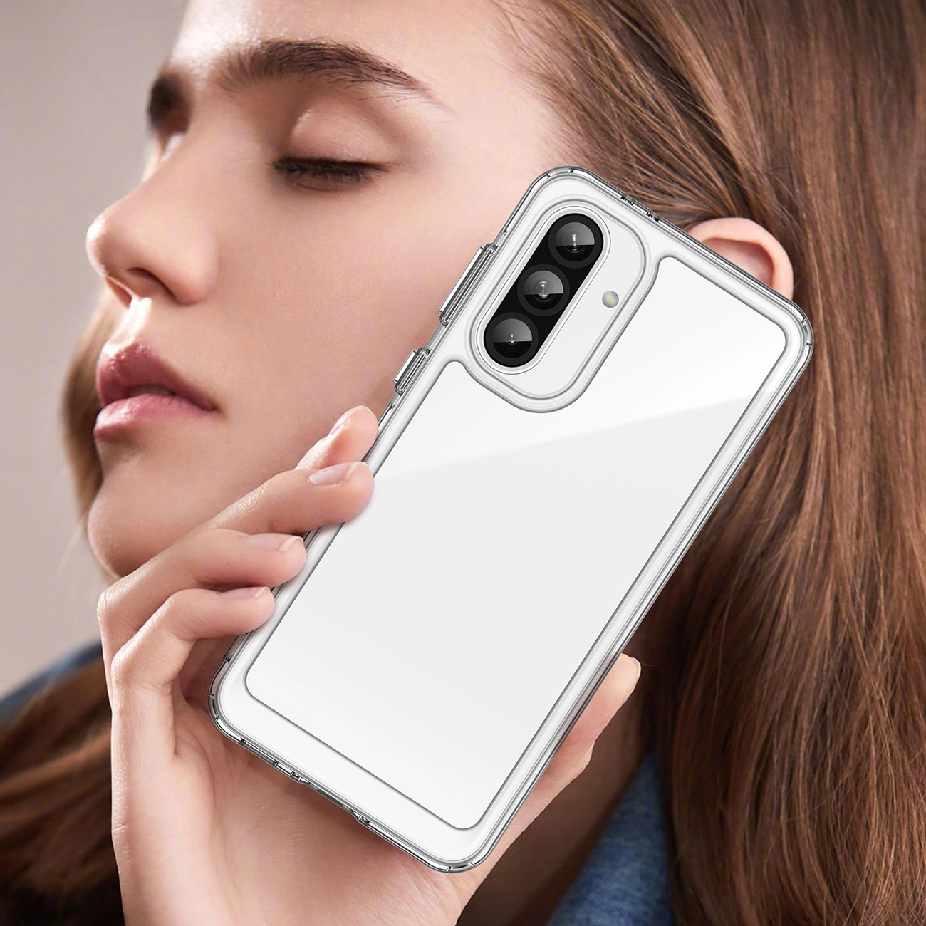 Eine Frau hält eine transparente Handyhülle. Die Hülle befindet sich auf einem Telefon mit drei Objektiven. Die Frau hat lange, braune Haare und trägt ein blaues Hemd.