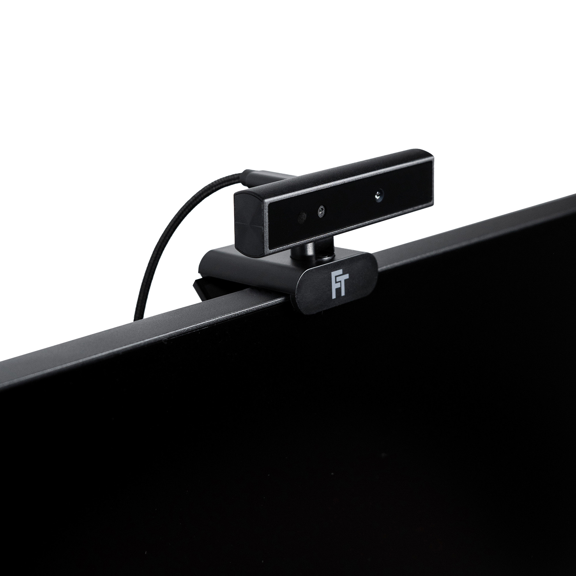 Eine Webcam ist auf einem schwarzen Bildschirm montiert. Die Webcam ist dunkelgrau mit schwarzem Kabel. Weißer Hintergrund.