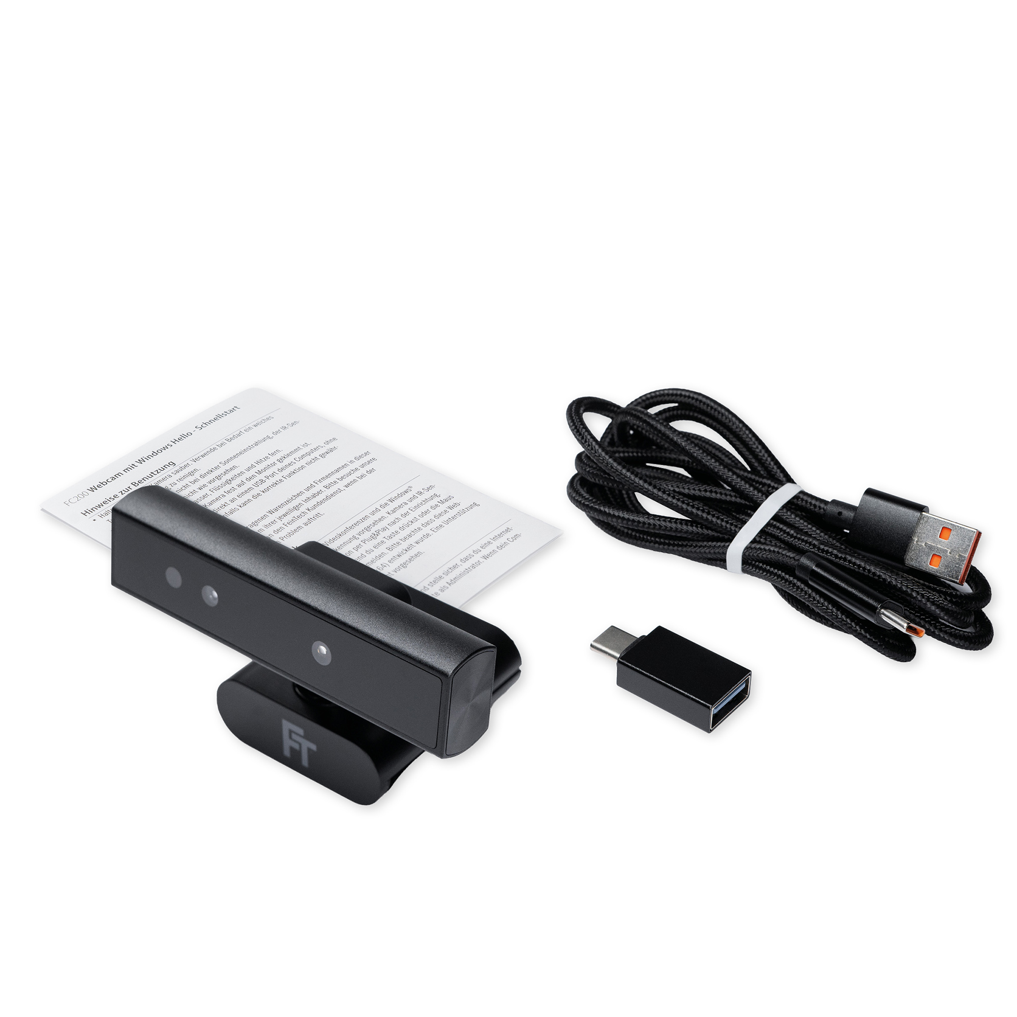 Eine schwarze Webcam, ein Kabel und ein Adapter auf Weiß. Die Webcam hat einen Ständer. Ein Papier ist im Hintergrund.