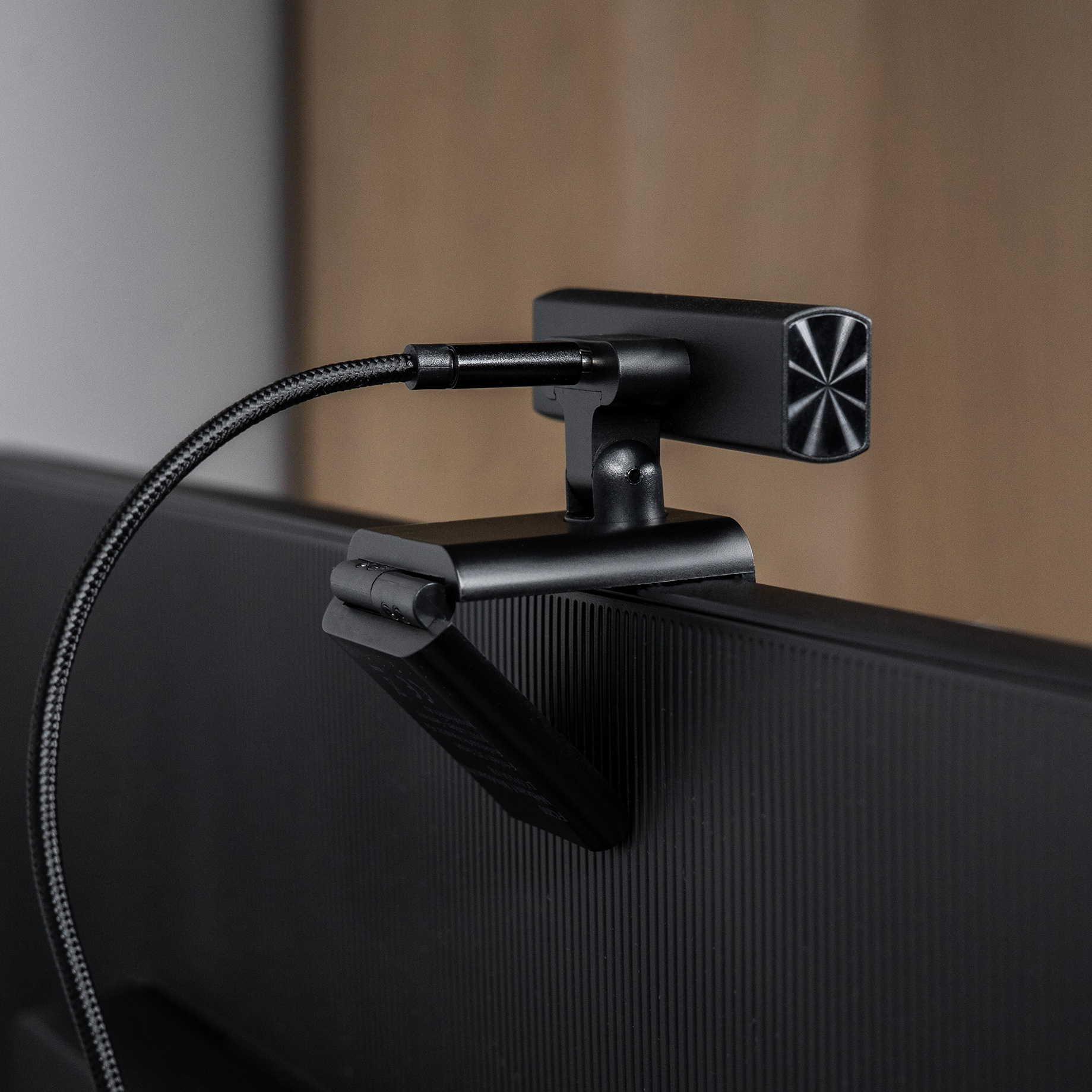 Eine schwarze Webcam, die an einem schwarzen Monitor befestigt ist. Die Webcam hat ein sternförmiges Design. Ein schwarzes Kabel ist sichtbar.