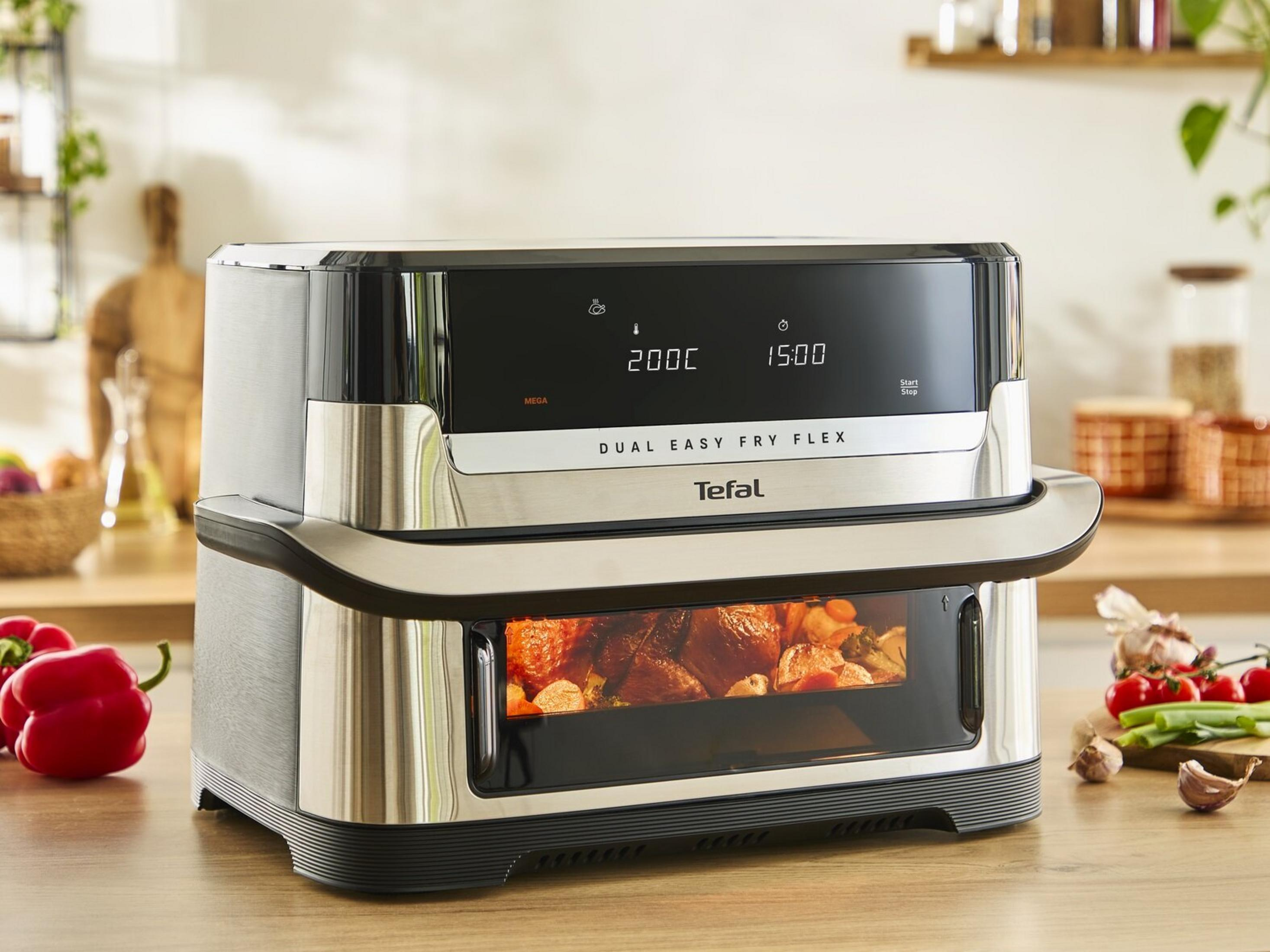 Frytkownica beztłuszczowa Tefal Dual Easy Fry Flex z jedzeniem, na drewnie, z warzywami obok.