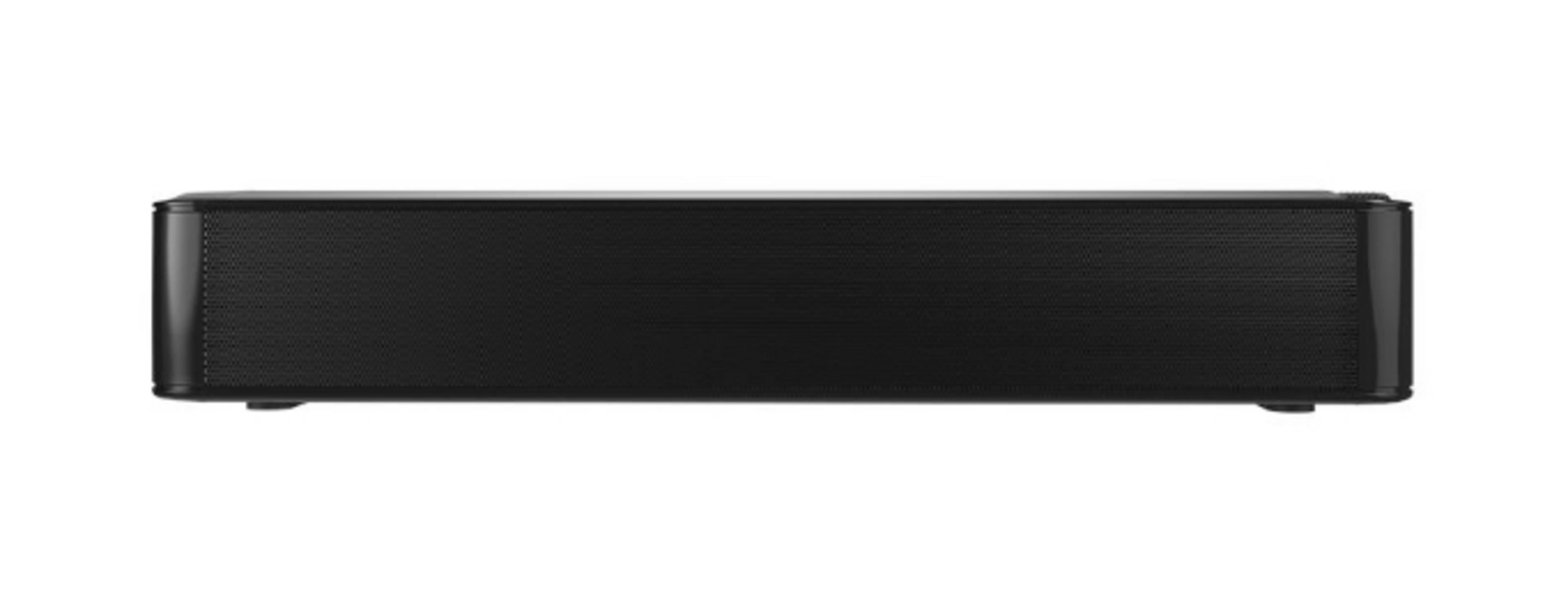 Una barra de sonido negra rectangular. Tiene una rejilla frontal, bordes redondeados y está sobre una superficie blanca.