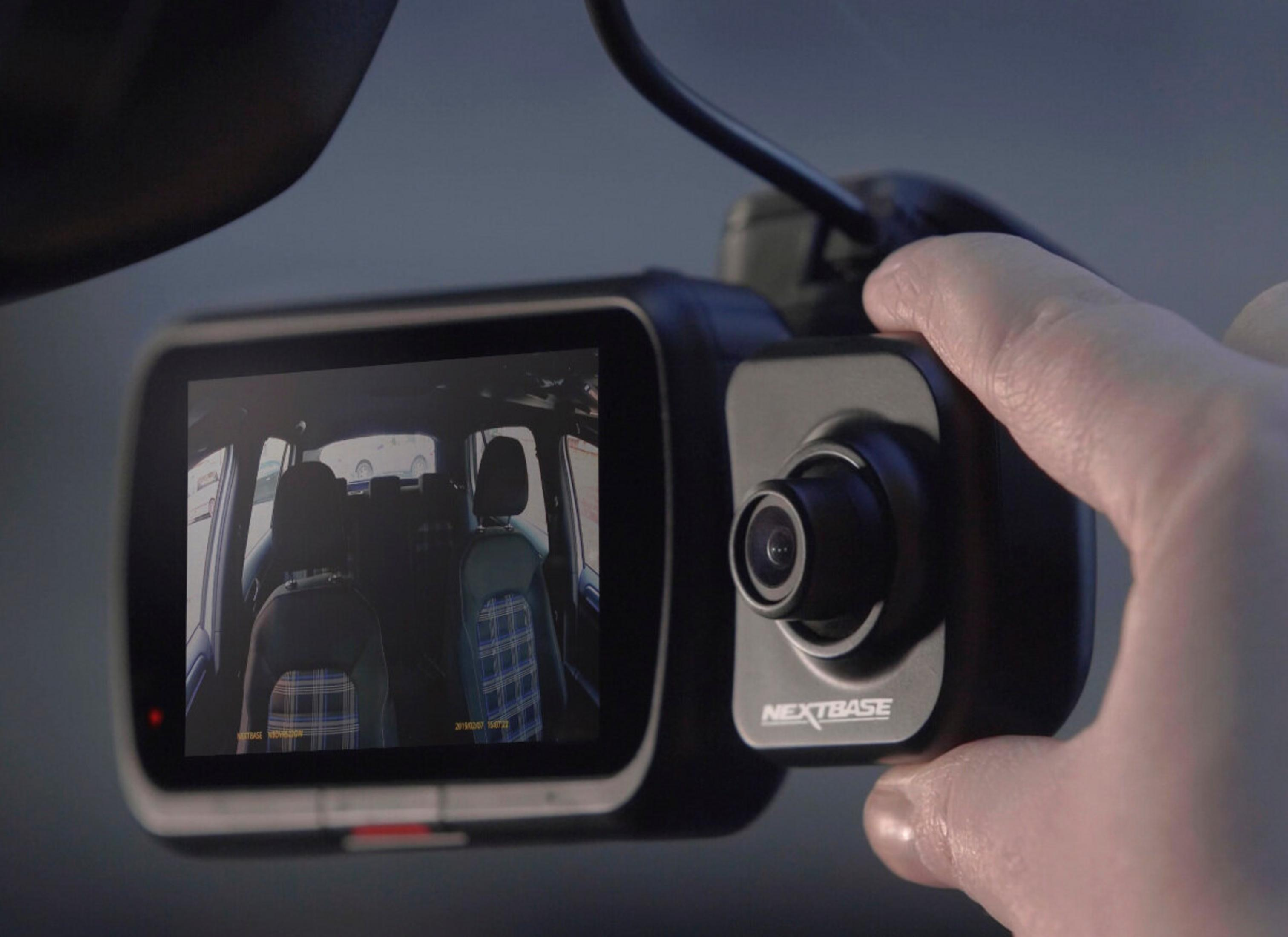 Dashcam in auto, mostra l'interno del veicolo. Una mano tiene la dashcam. Lo schermo mostra l'interno.