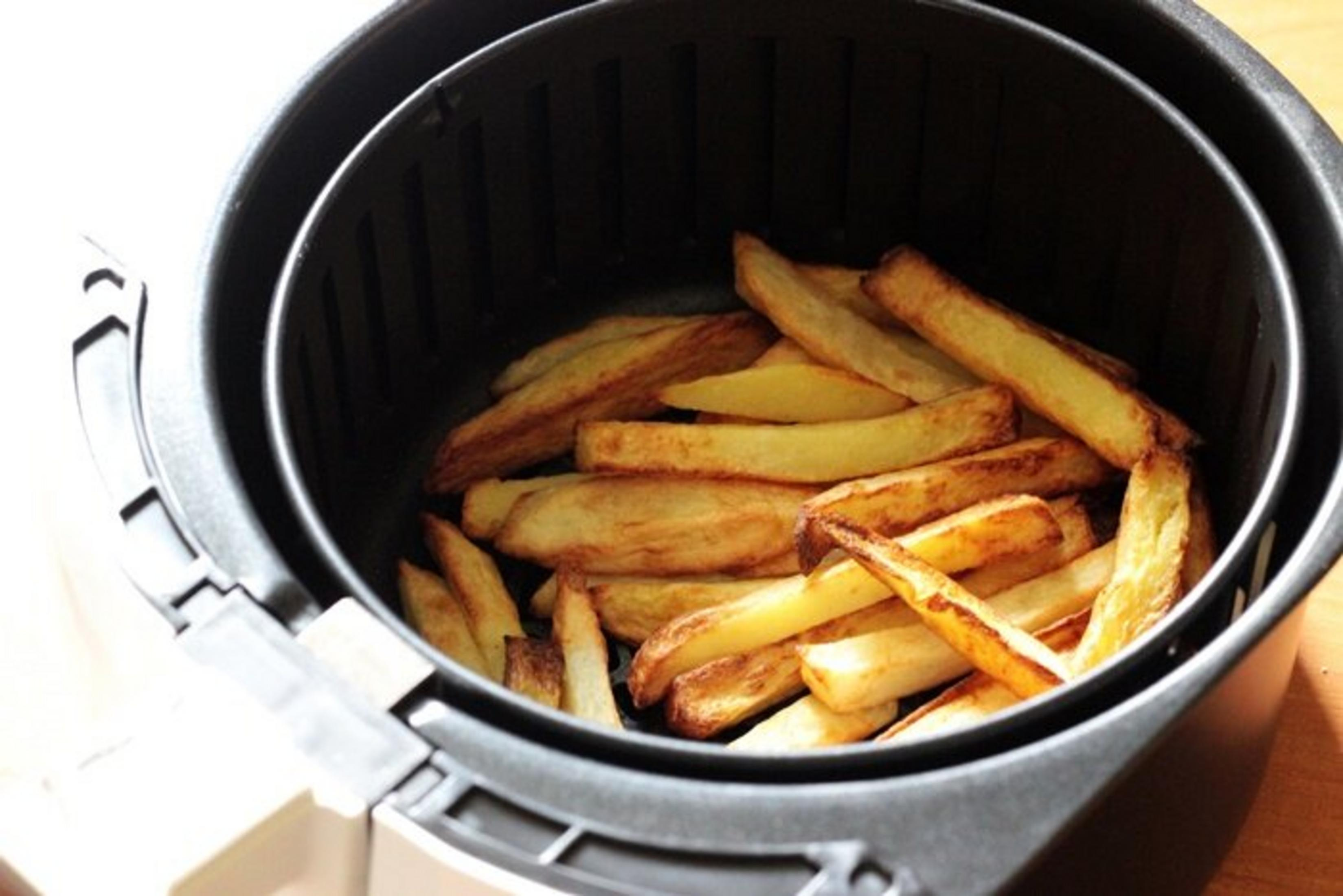 Ein Airfryer gefüllt mit goldbraunen Pommes Frites. Die Pommes sind knusprig und sehen köstlich aus.