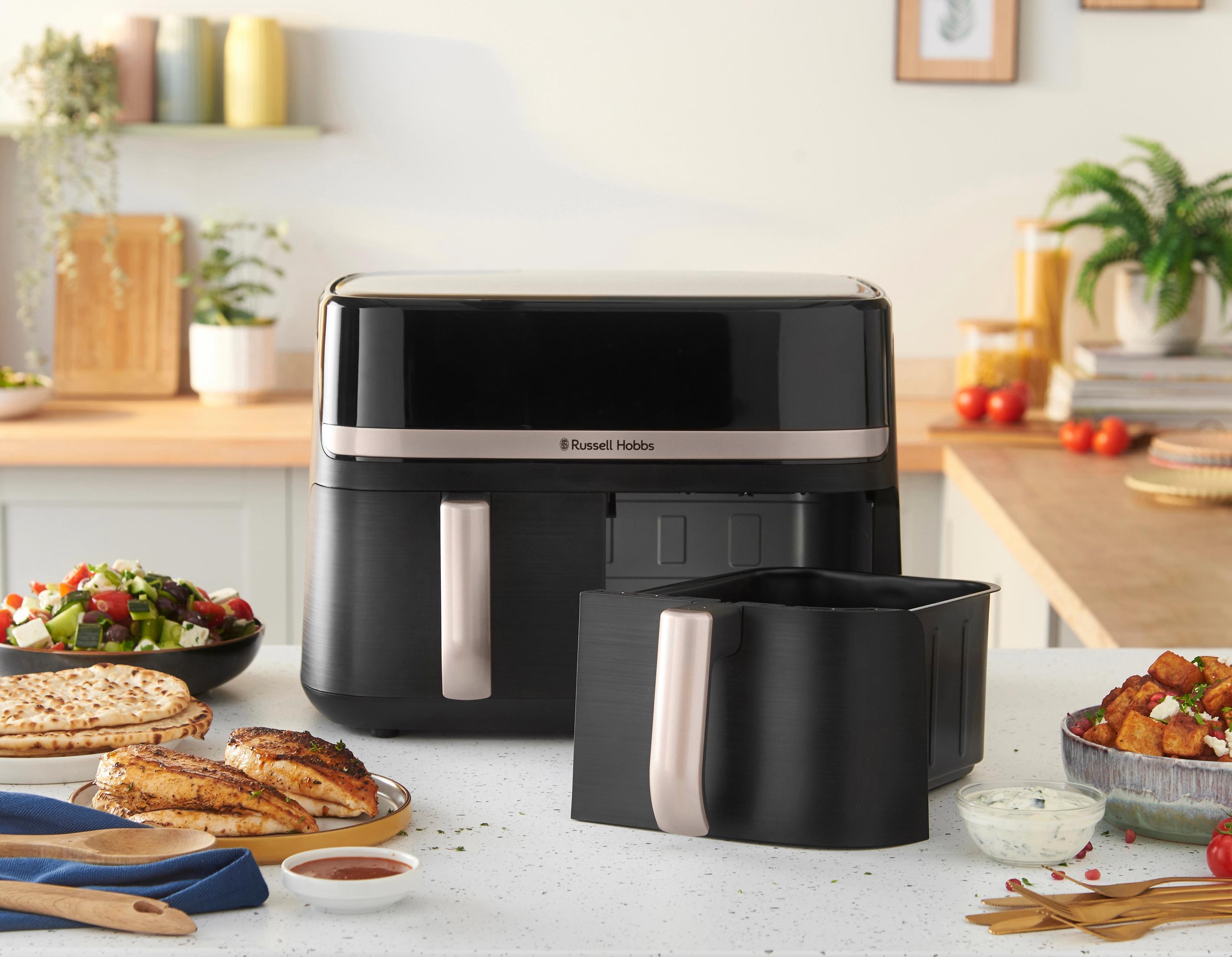 Czarna frytownica na blacie z jedzeniem. Widoczna sałatka, kurczak i ziemniaki. Otoczenie kuchni.