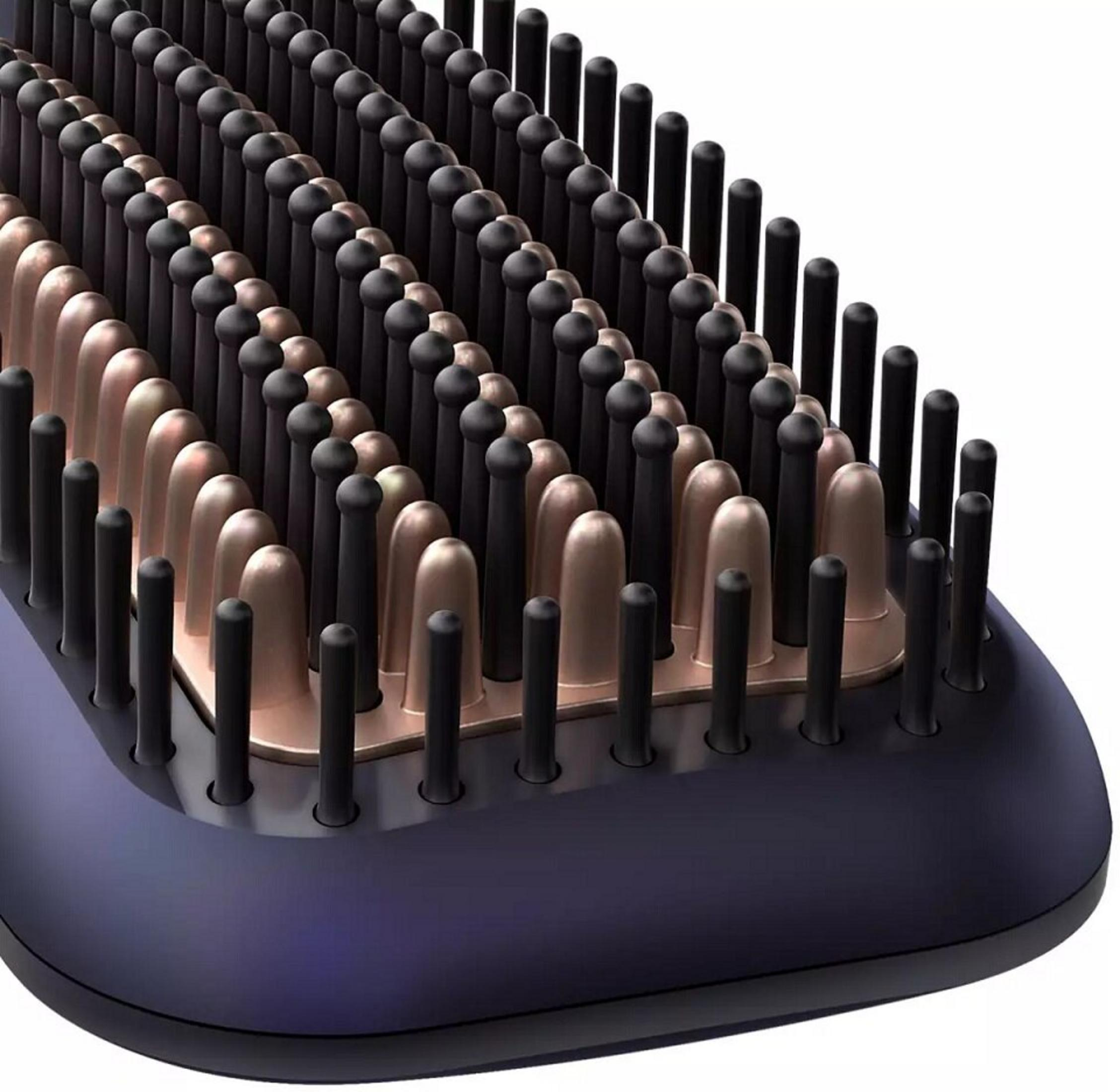 Nahaufnahme einer Haarglättungsbürste. Schwarze und bronzefarbene Borsten sind in Reihen auf einem lilafarbenen Sockel angeordnet.