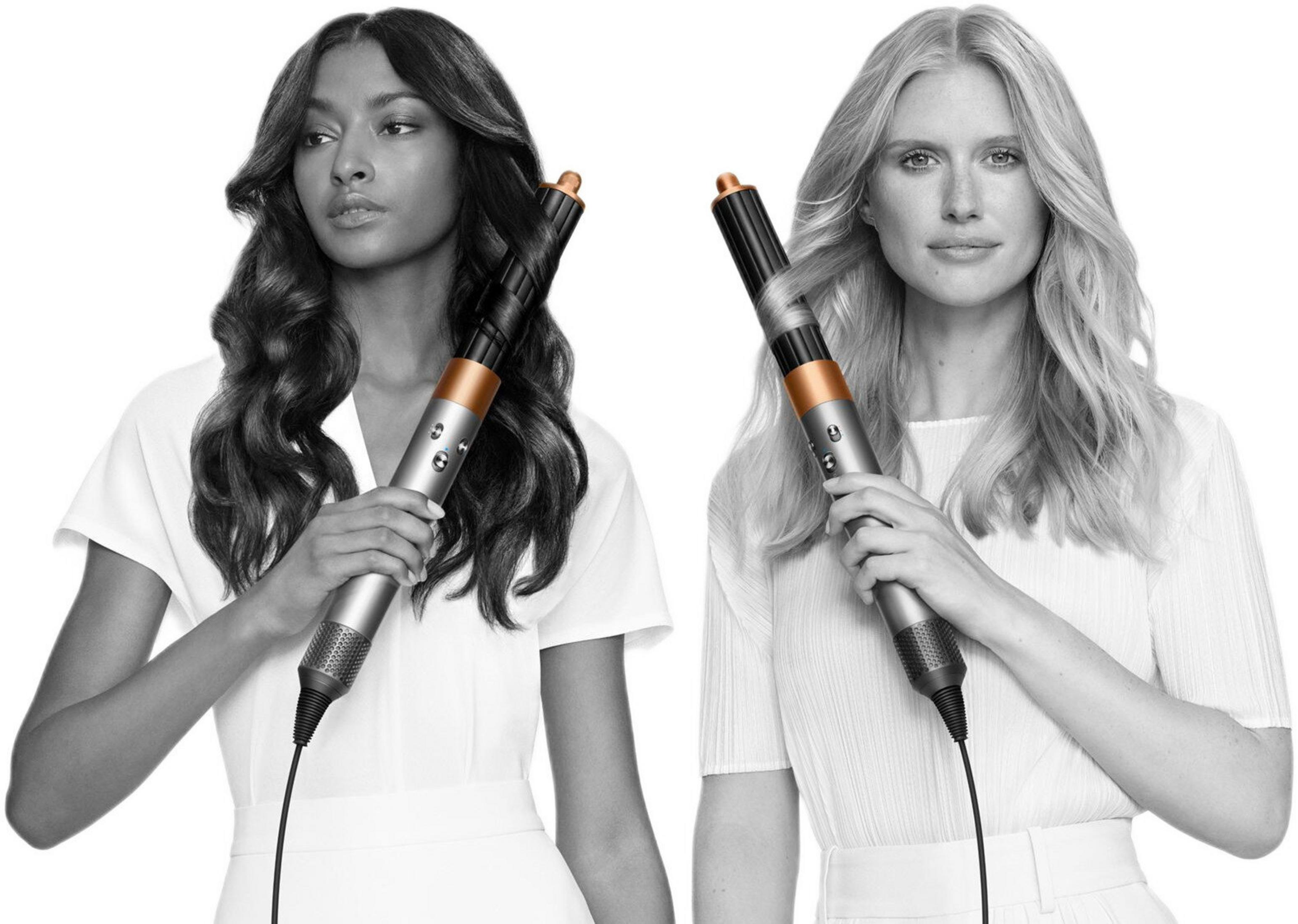 Due donne tengono degli styler per capelli. Una ha capelli scuri e ricci, l'altra biondi e ondulati. Sfondo bianco.