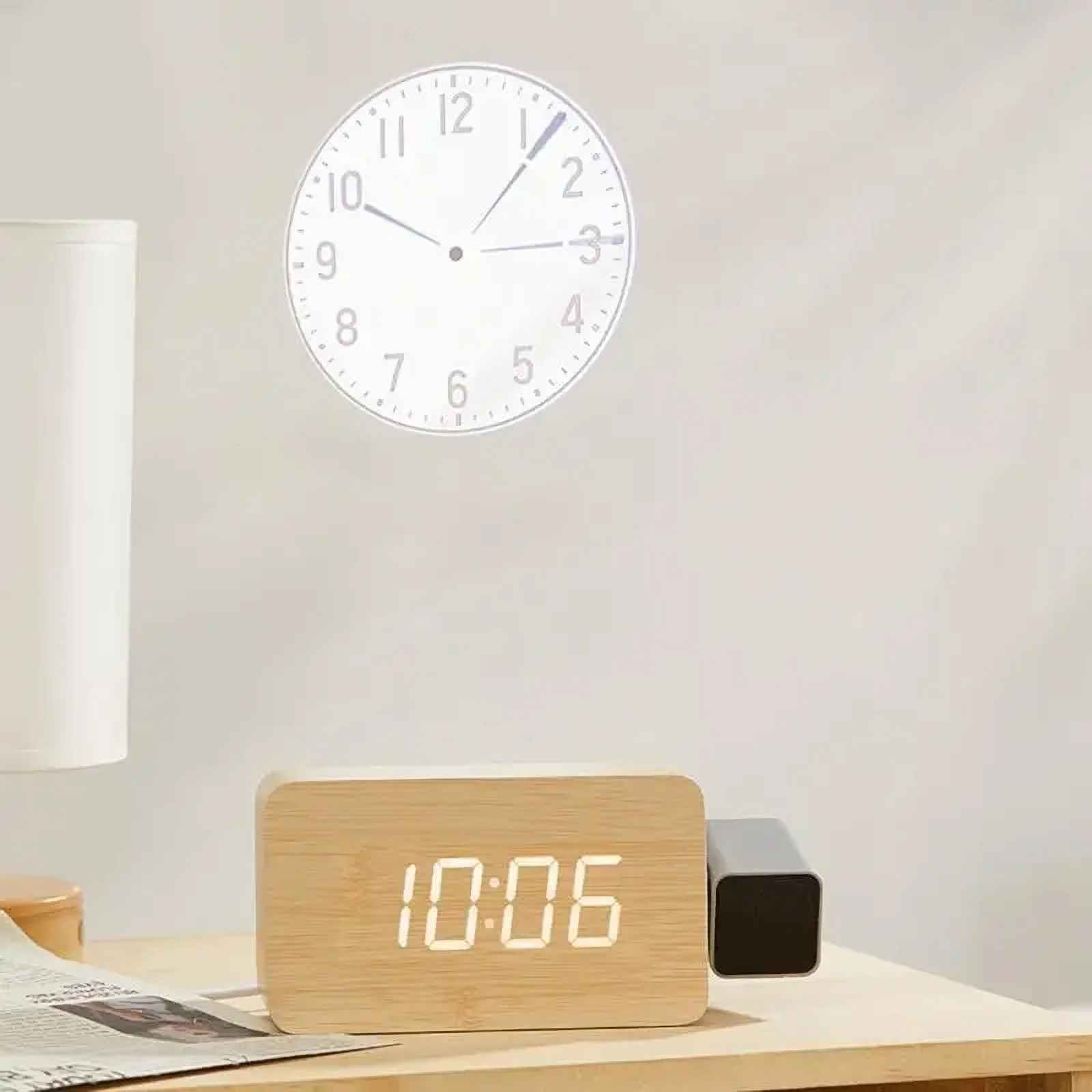 Digitaluhr aus Holz zeigt 10:06 auf einem Tisch. Eine projizierte Uhr ist an der Wand. Links ist eine Lampe.